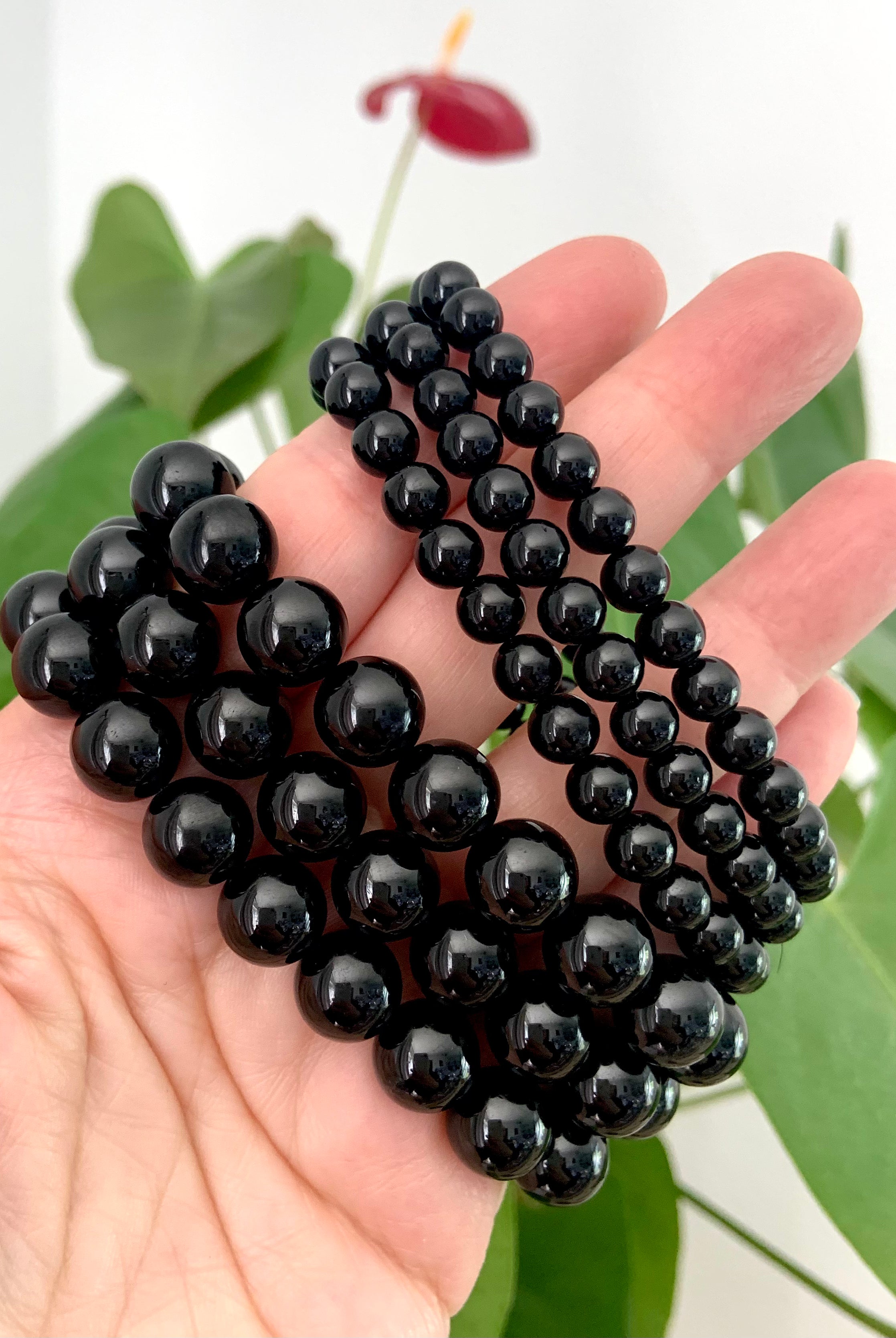Side view of two sets of Black Tourmaline bracelets on a hand — showing glossy bead sizes 10–11mm and 6–7mm for sizing reference