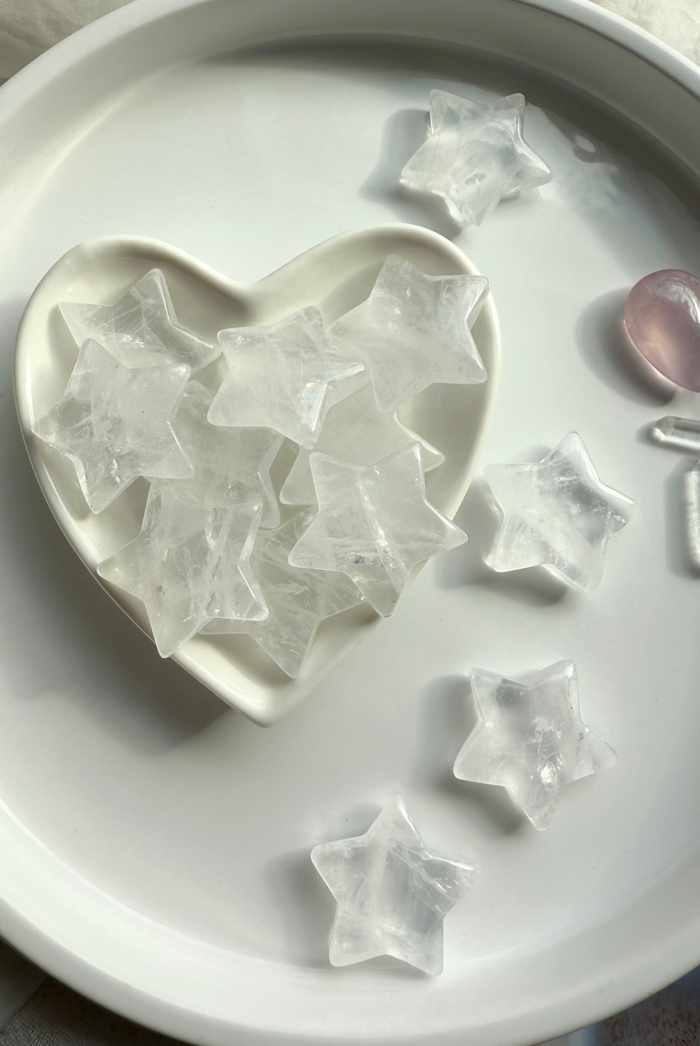Clear Quartz stars filling a white heart bowl surrounded by more stars, healing crystals for clarity, light, and spiritual protection