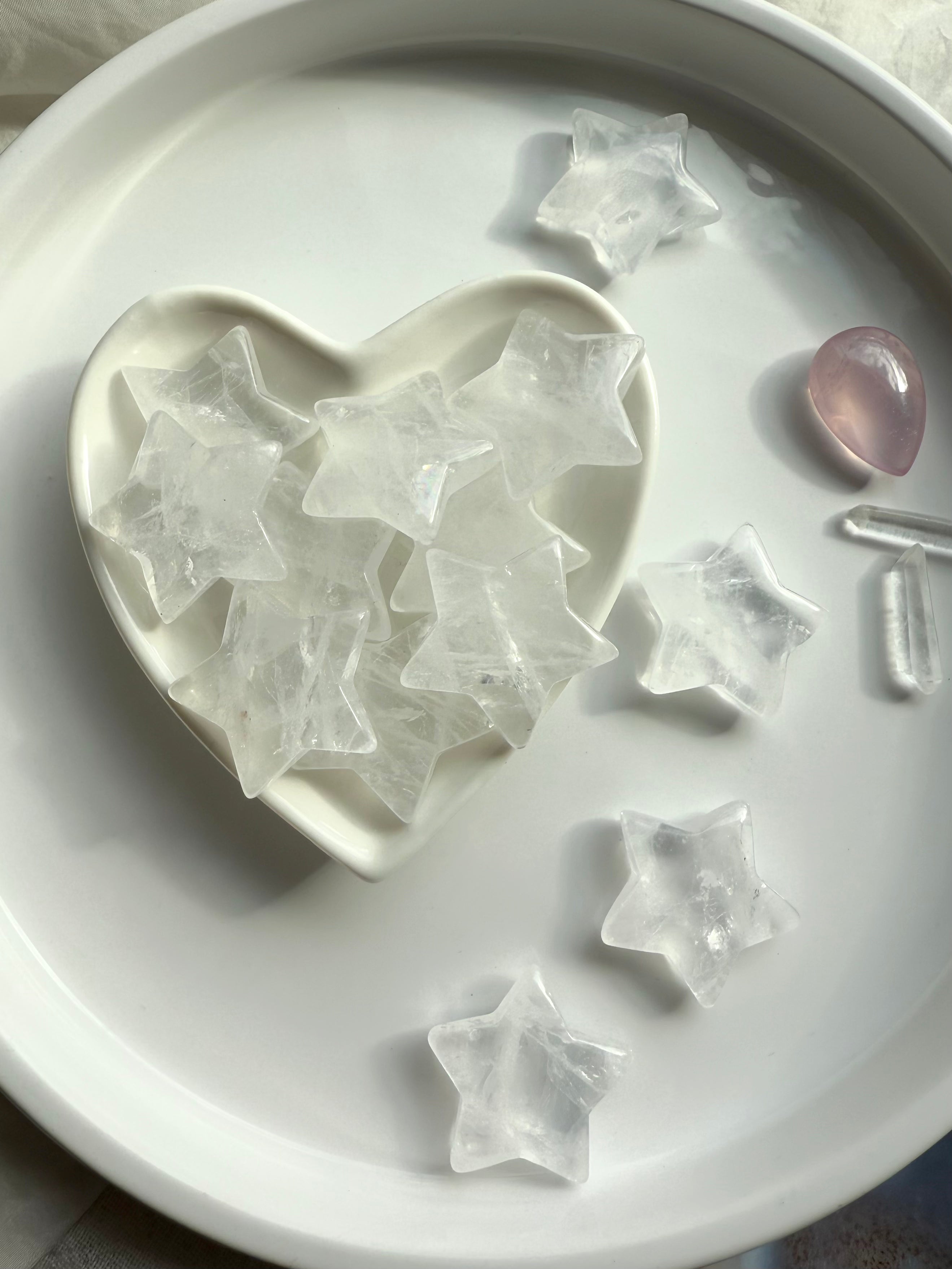 Clear Quartz stars filling a white heart bowl surrounded by more stars, healing crystals for clarity, light, and spiritual protection