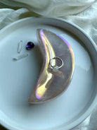 Aura Rose Quartz crescent moon bowl with opalescent lilac shimmer holding a ring
