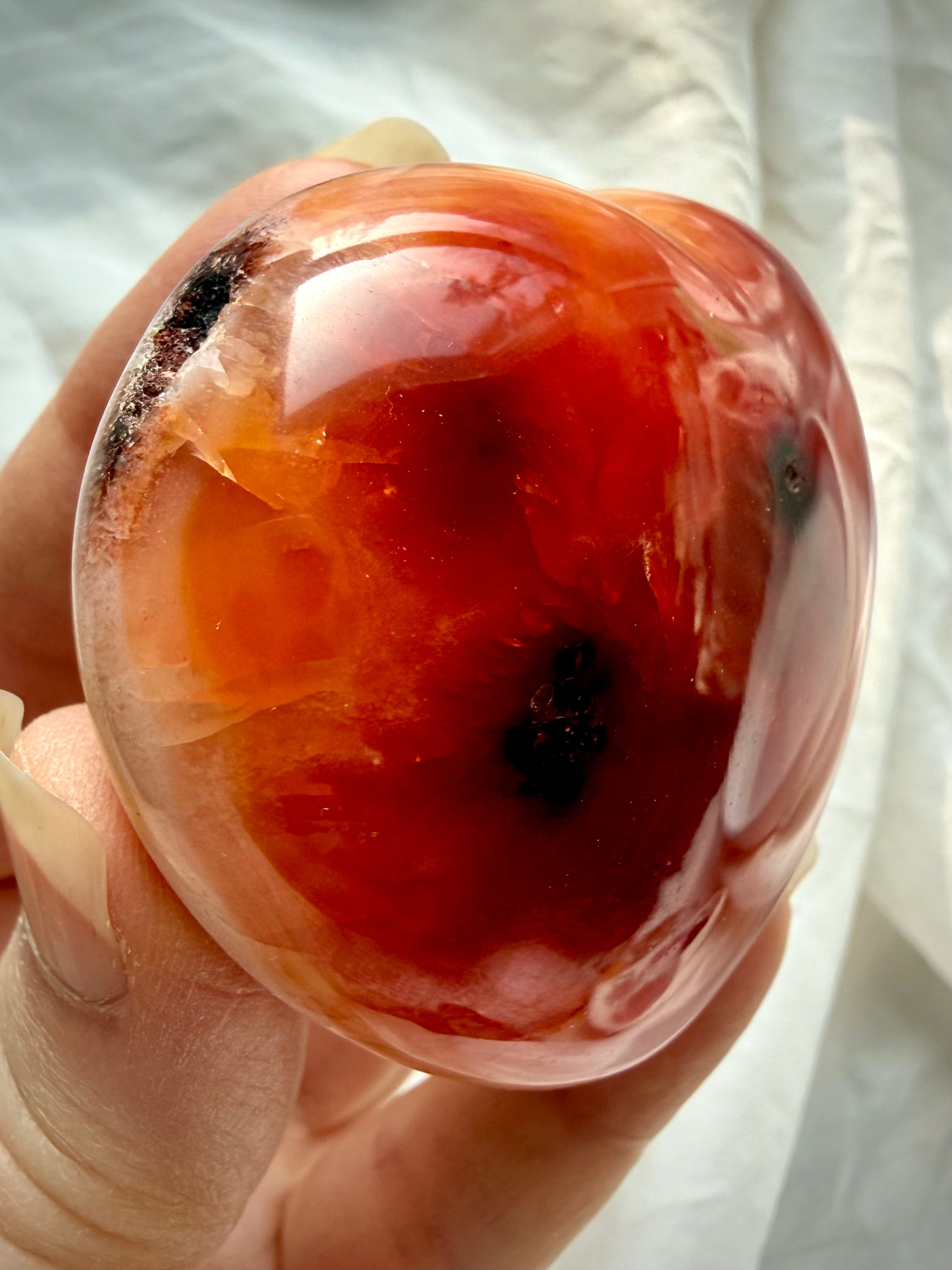 Side view of one of a kind Carnelian heart showing glossy polish, natural druzy cave detail, and raw texture spot on edge