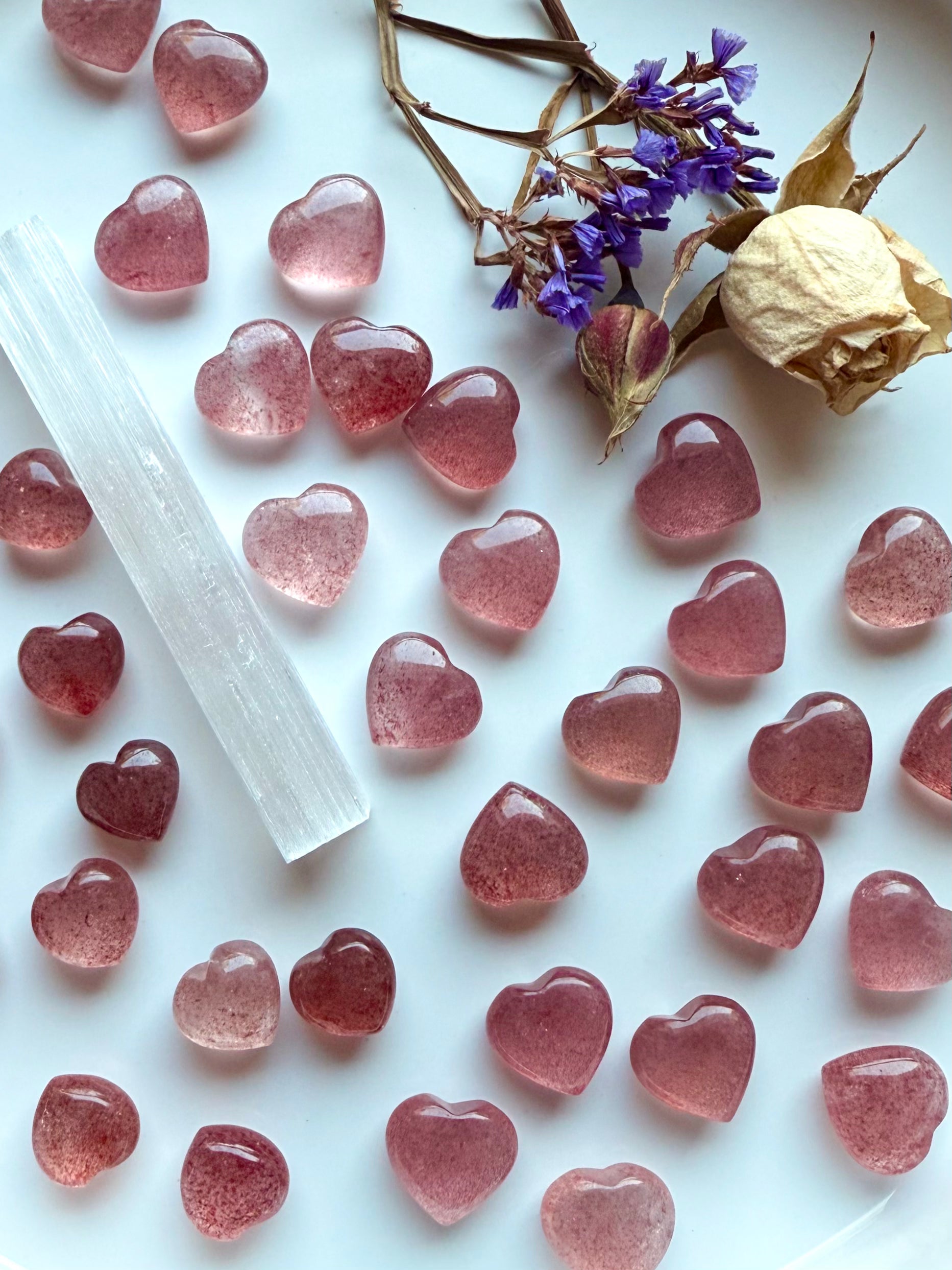 Closeup of sparkly Strawberry Quartz hearts on a white plate with selenite and roses — tanzberry quartz crystals for heart chakra healing, love, and emotional balance.