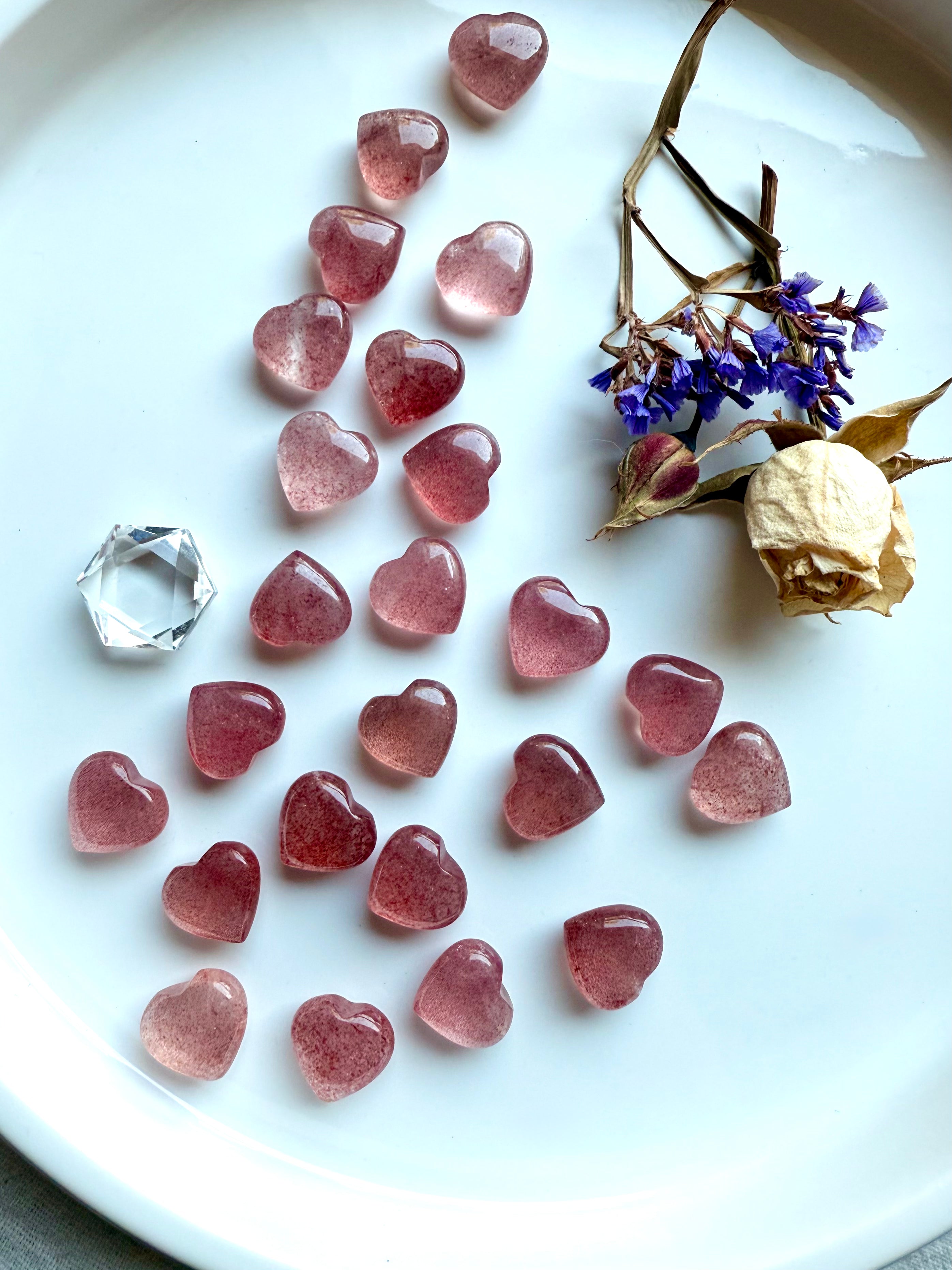 Array of Strawberry Quartz mini hearts on a white plate with flowers — tanzberry quartz crystals for heart chakra healing, love, and emotional balance.