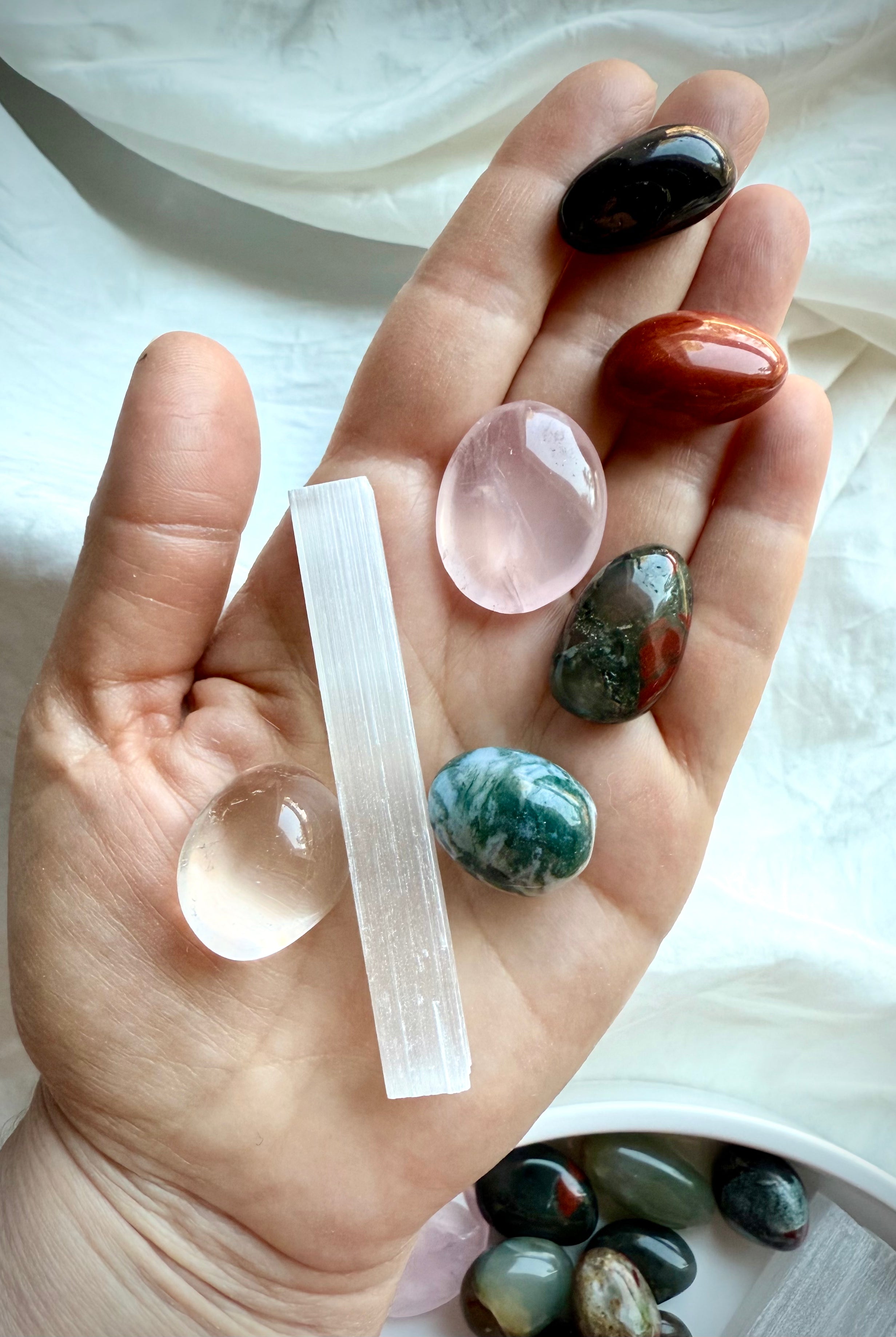 Get Well crystals including Red Jasper, Rose Quartz, and Moss Agate shown in hand for scale