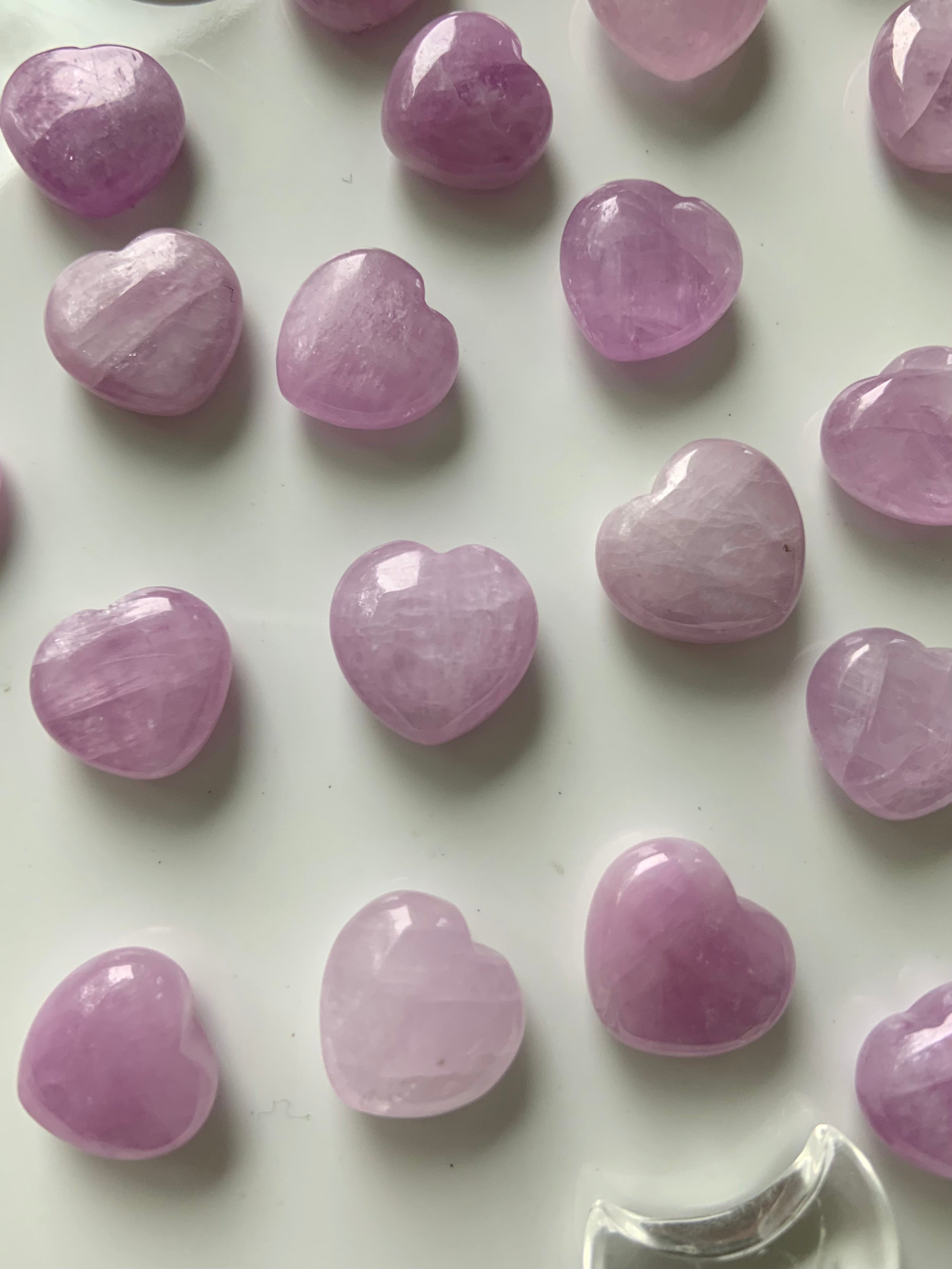 Close-up of mini Pink Kunzite hearts on a white background β crystal hearts for peace, compassion & energetic balance.