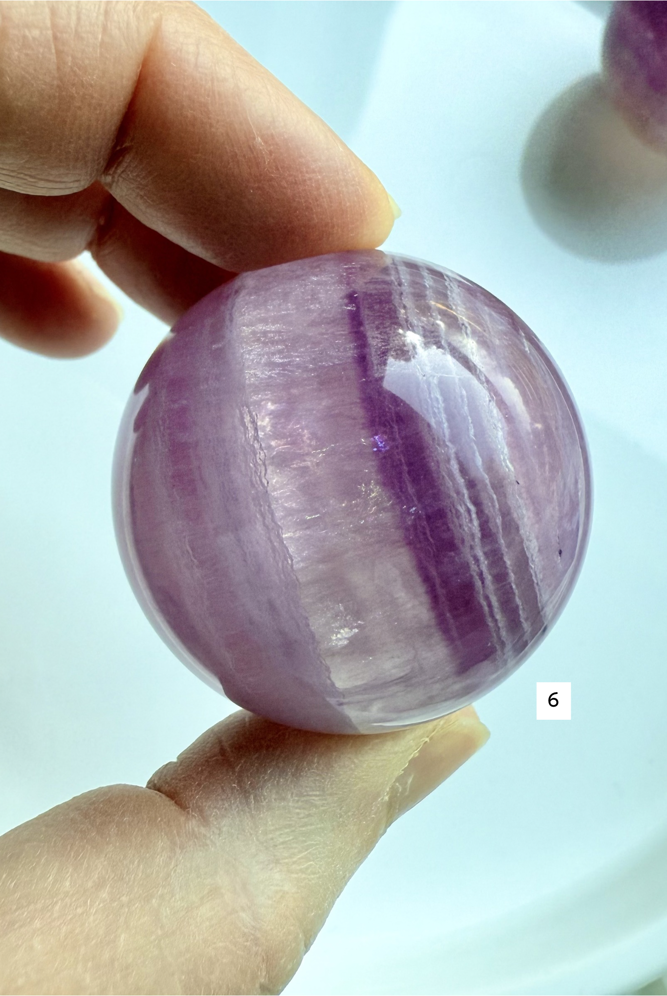 polished Candy Fluorite sphere with bold purple striping and soft translucent glow for spiritual clarity