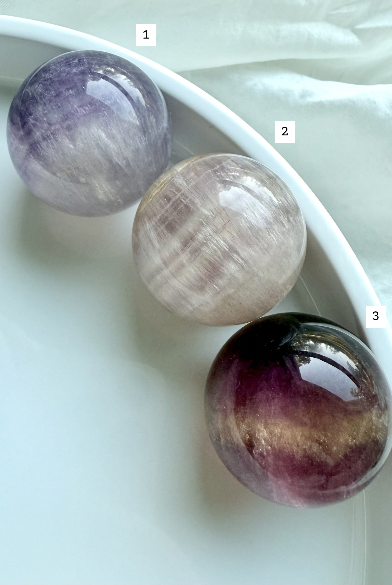 rare pink and purple Candy Fluorite spheres with silky layered patterns displayed on white dish
