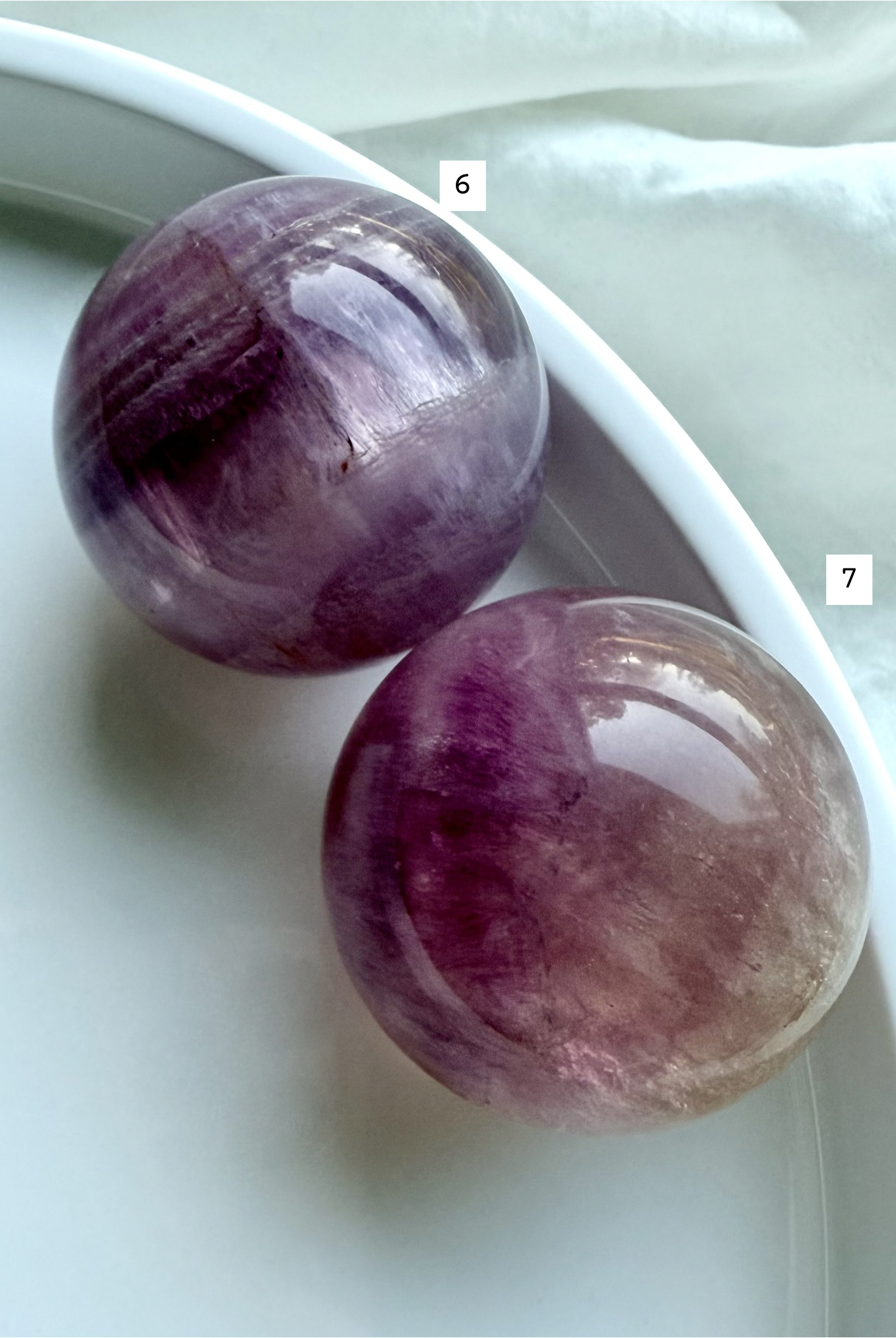 pair of polished Candy Fluorite spheres with silky magenta banding and luminous translucent crystal layers