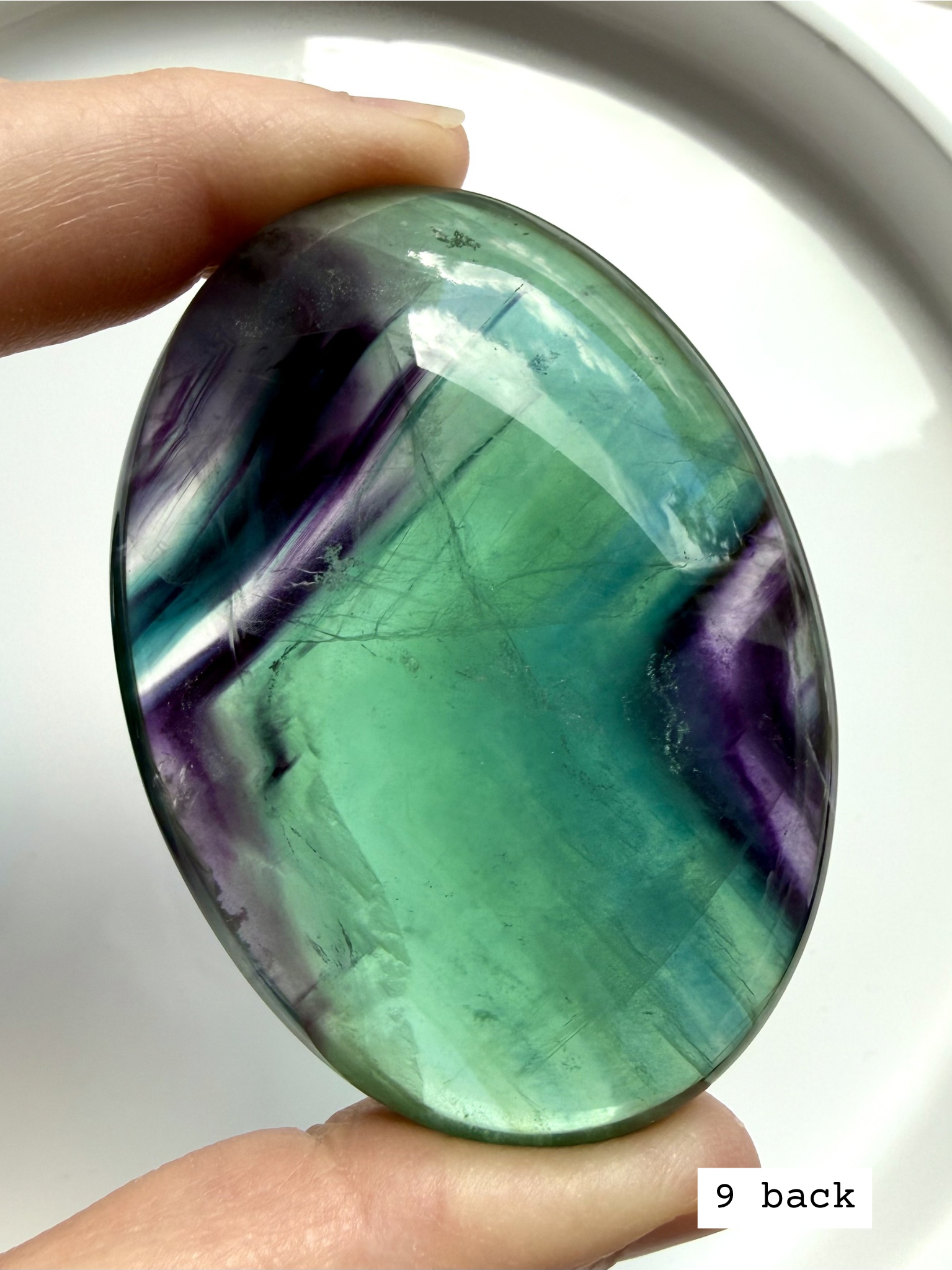 Teal fluorite palm stone #9 back view with vibrant blue green swirls and luminous glow in natural light