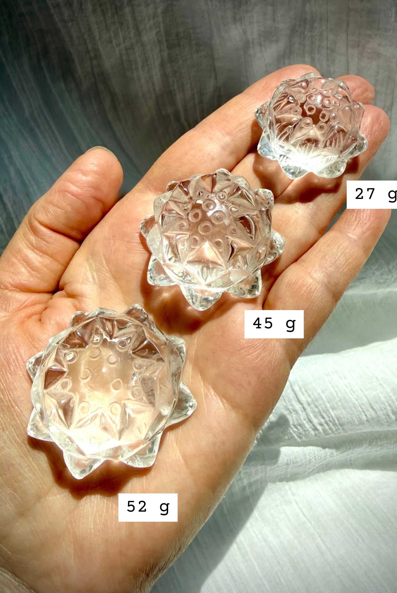 Small Clear Quartz crystal lotus flower carving held in hand marked with size, showing clarity and detailed petals