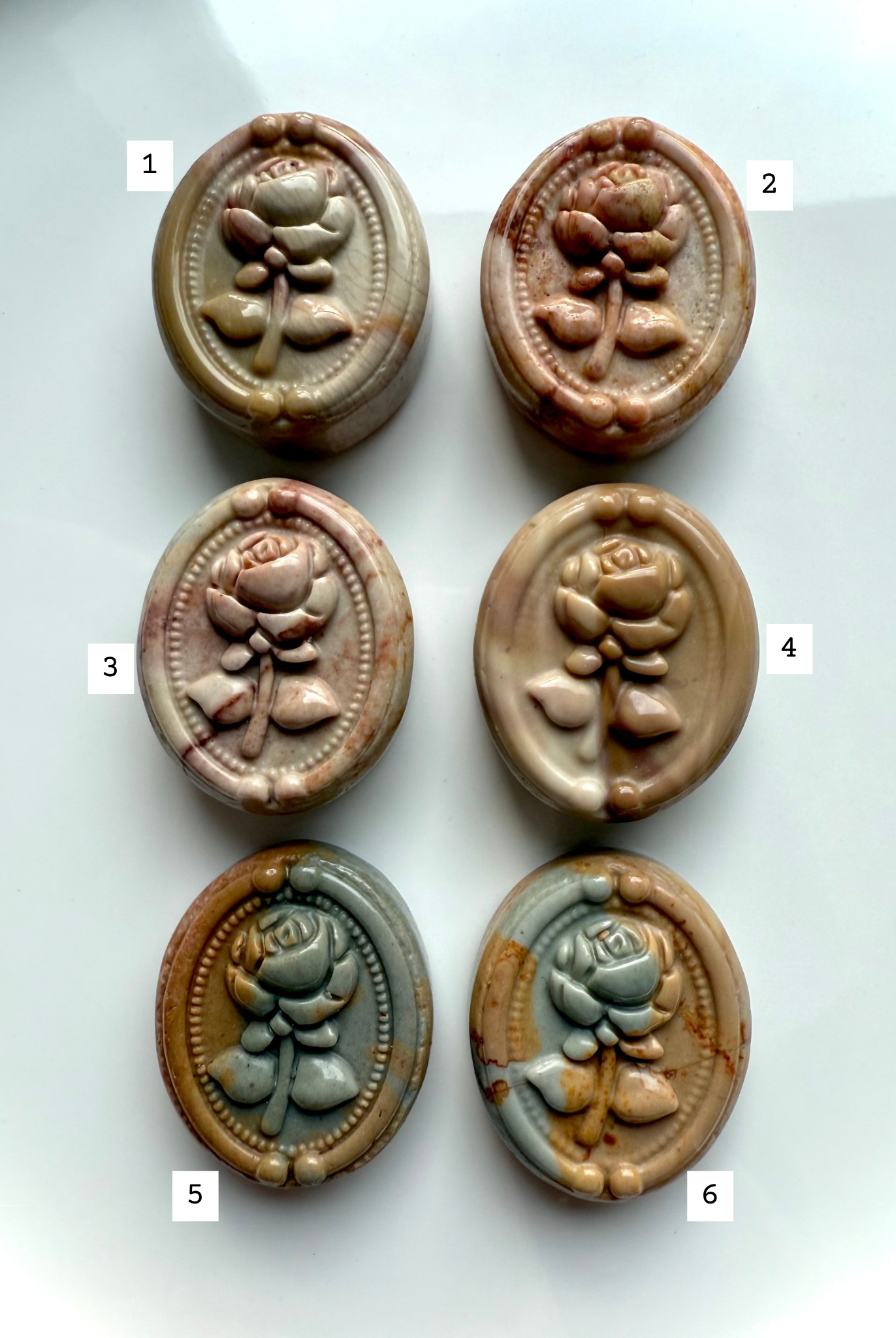 Polychrome Jasper rose cabochons in assorted natural colors arranged in two rows — carved crystal ovals for grounding, balance, and earth element healing.