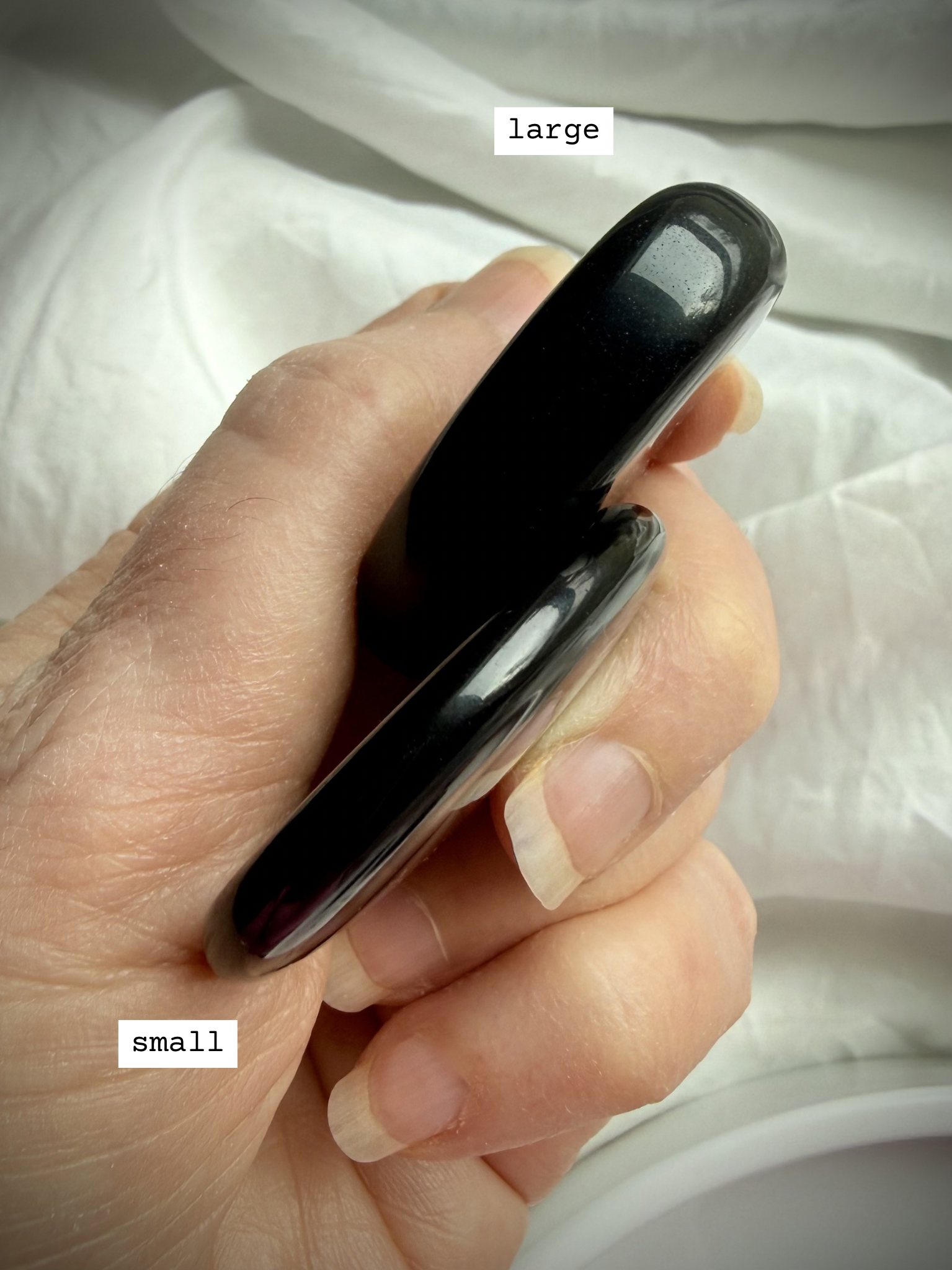 Size comparison of Black Obsidian worry stones held in hand – thumb stone for anxiety relief, grounding + chakra healing
