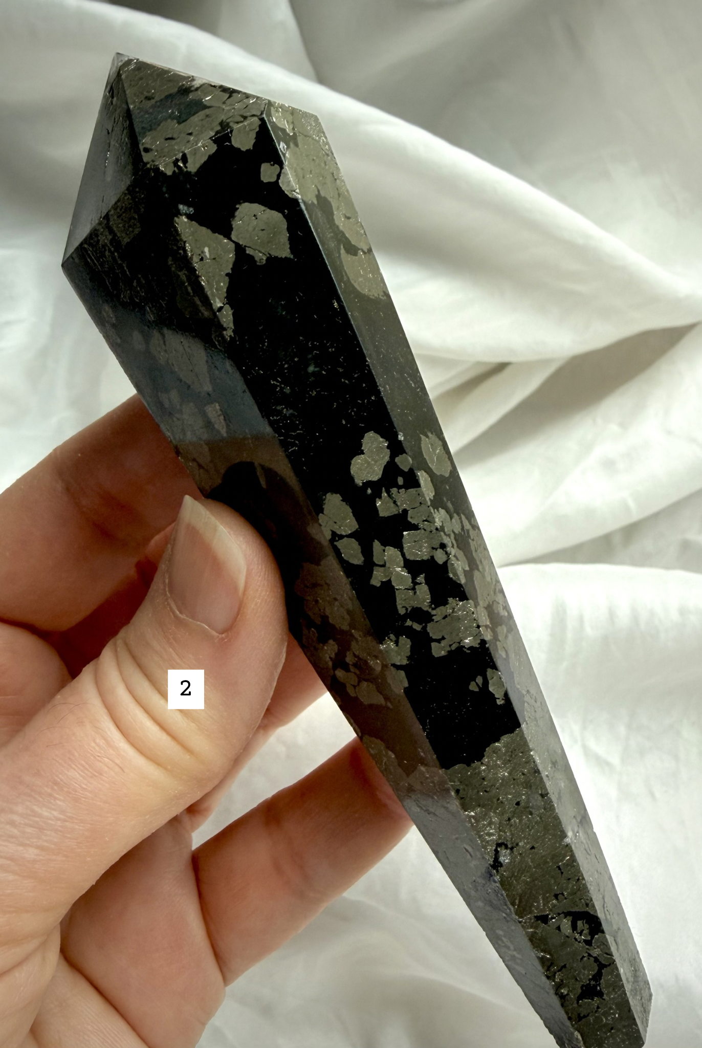 pyrite wand in black matrix held in hand polished crystal point option 2