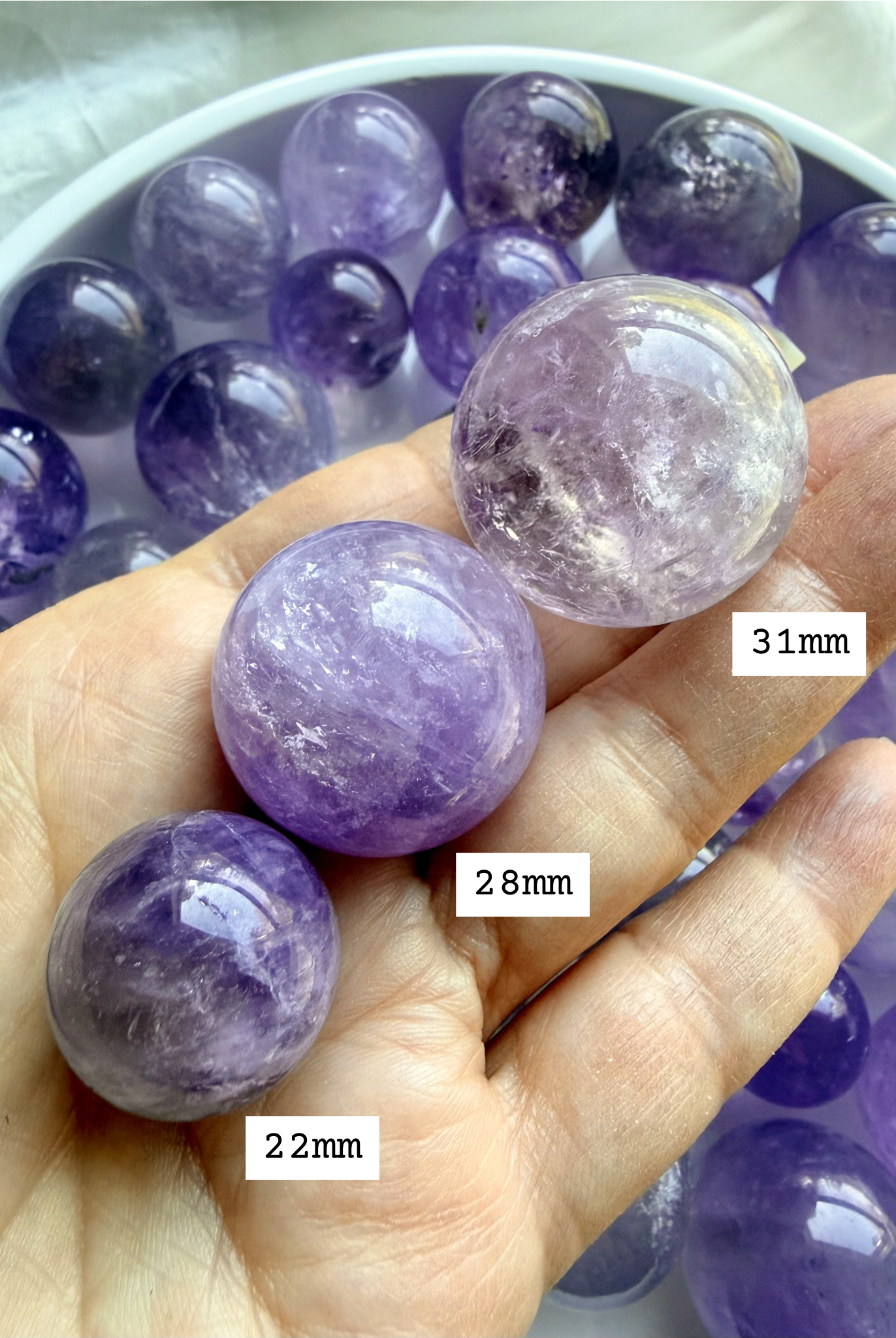 smoky amethyst mini spheres in hand showing size comparison of 22mm, 28mm, and 31mm small crystal balls with natural inclusions