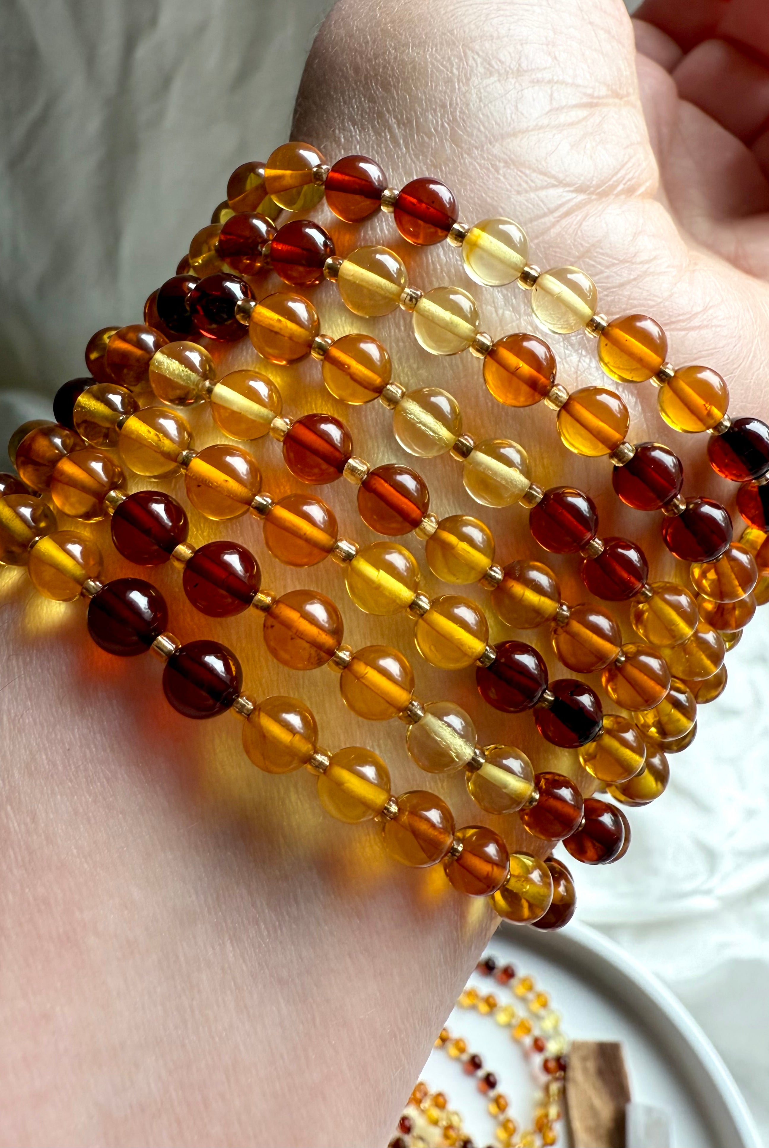 Close-up of polished Baltic amber bead bracelets in warm golden, honey, and cognac tones – Solar Plexus crystal jewelry for energy, confidence + vitality