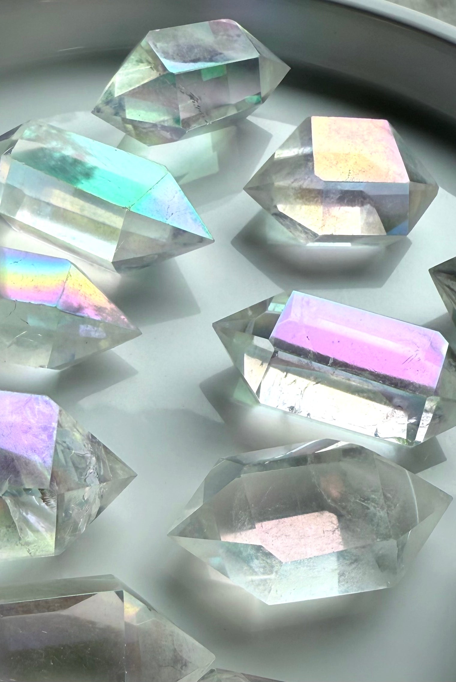 Shimmering Angel Aura Quartz double terminated points with pastel rainbow hues displayed in natural light