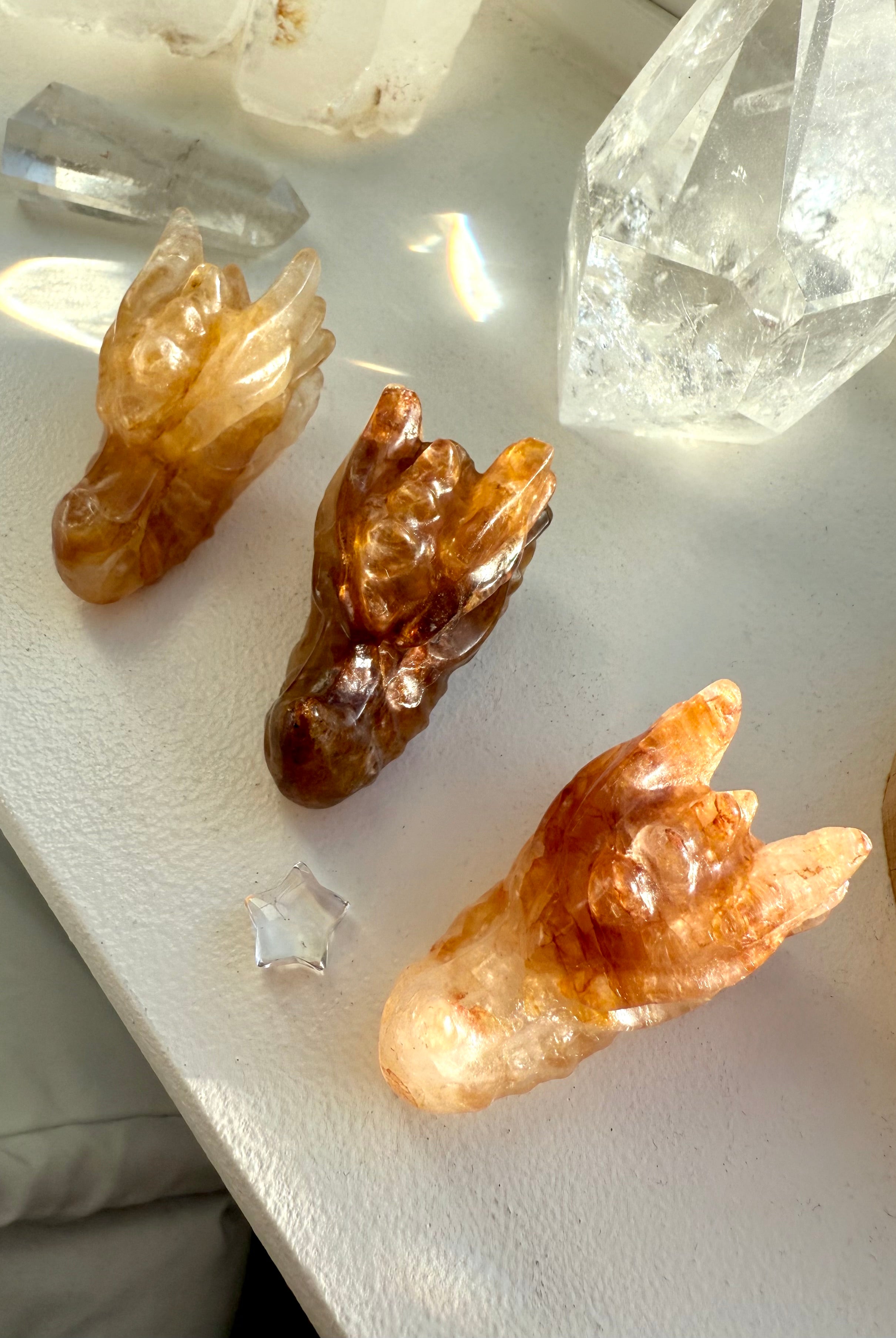 Overhead view of three small Golden Healer Quartz dragon head carvings on windowsill — crystal figurines for Solar Plexus healing, energy work, and spiritual décor.