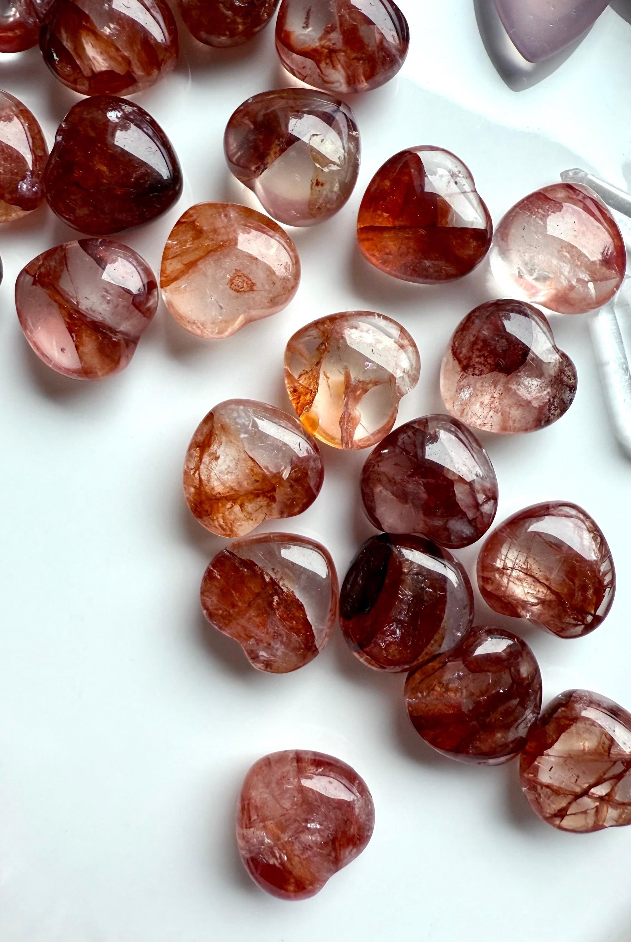 Collection of red Hematoid Quartz hearts in natural light, shown on a white plate