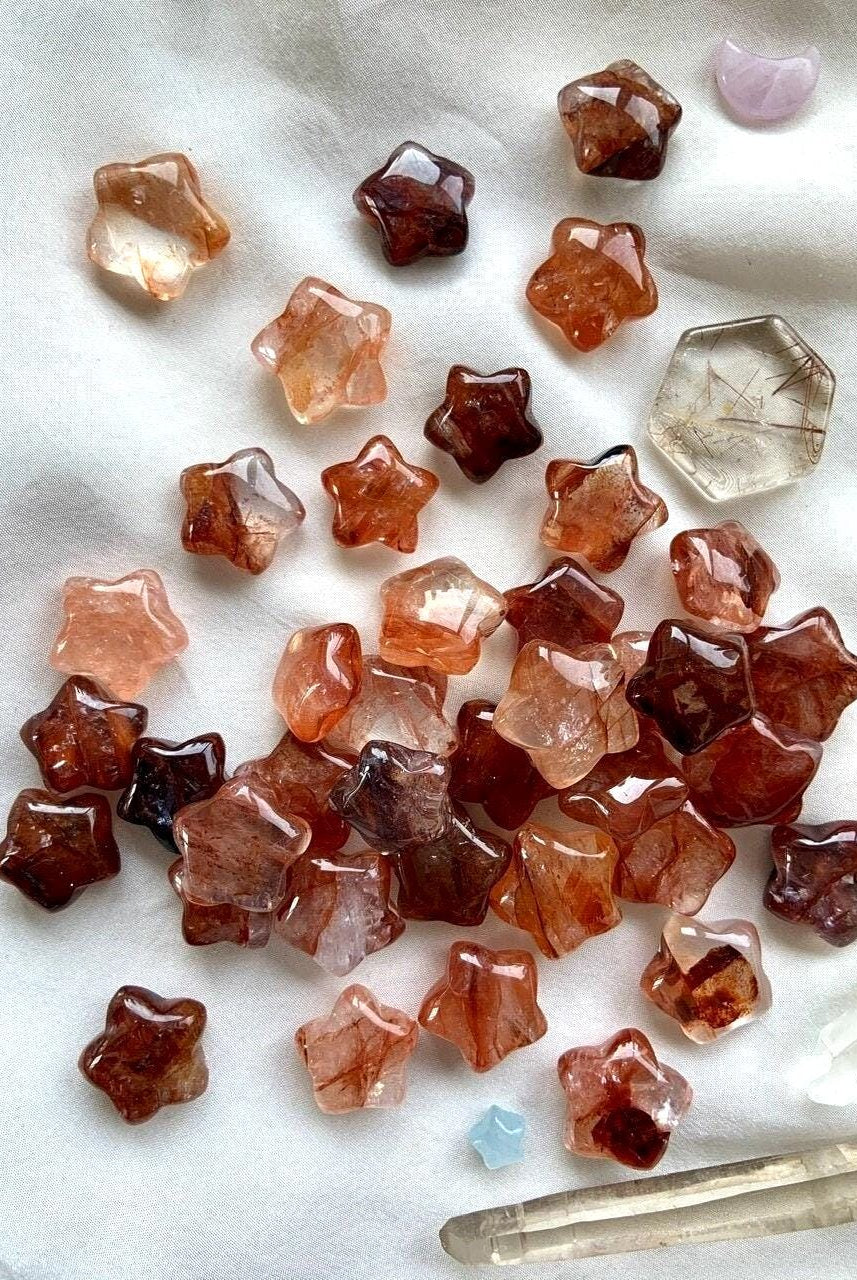 An array of Mini Fire Quartz Crystal Stars shown on a white background with some other crystals