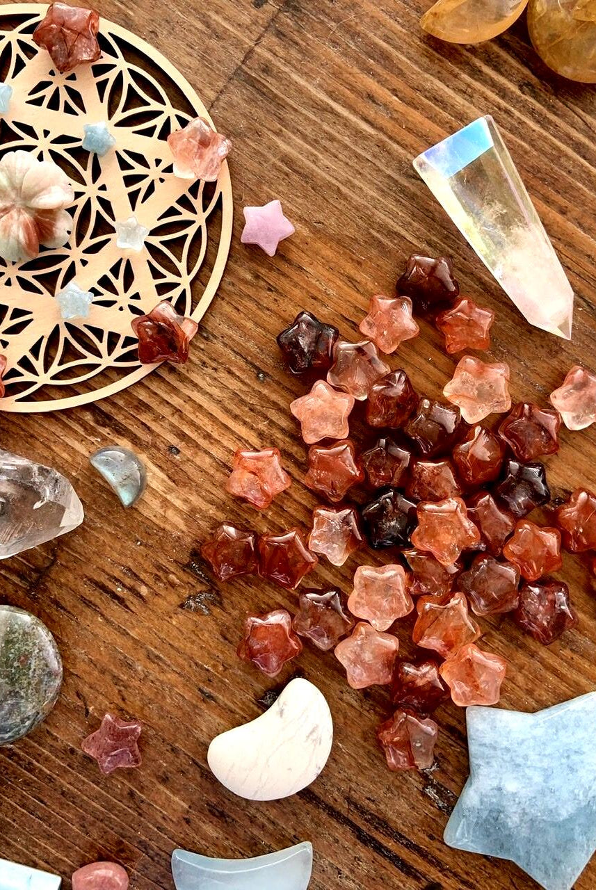 Mini Fire Quartz Crystal Stars shown on a wood table with a crystal grid + crystal collection