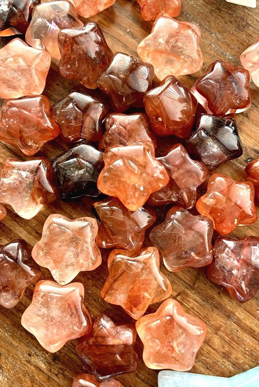 A close up of our vibrant red fire quartz mini crystal star shapes shown on a wood table