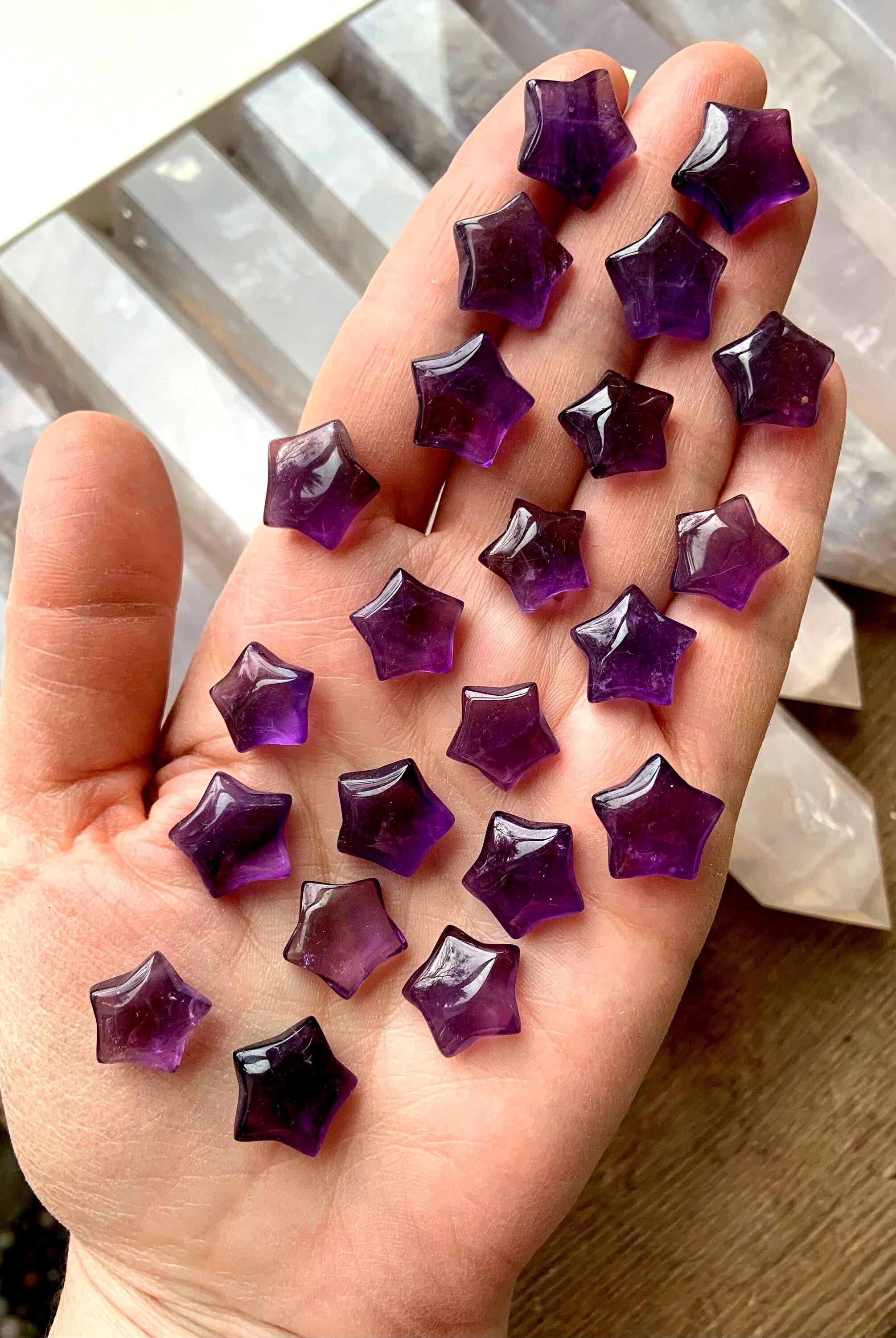 Mini sized purple amethyst stars shown on my hand with pretty crystals in the background