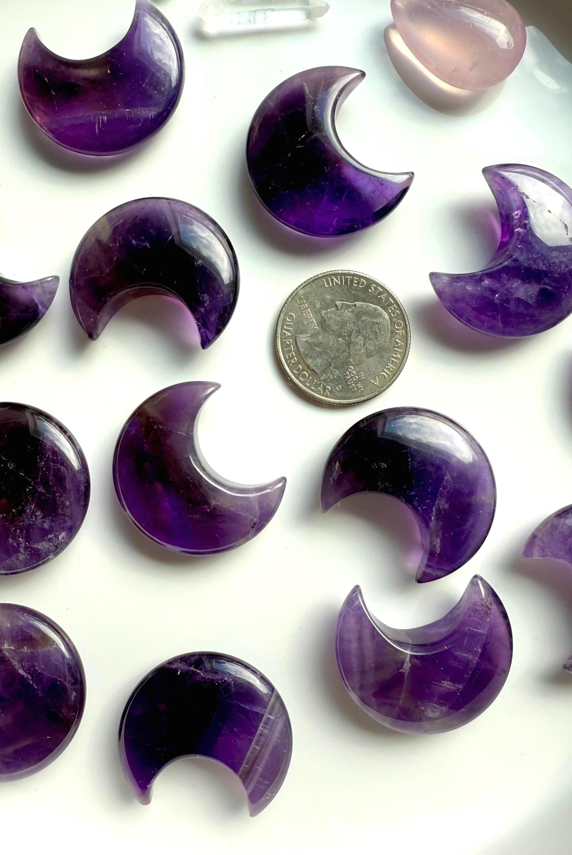 High quality deep purple Dream Amethyst Moons shown on a white plate with a quarter for scale