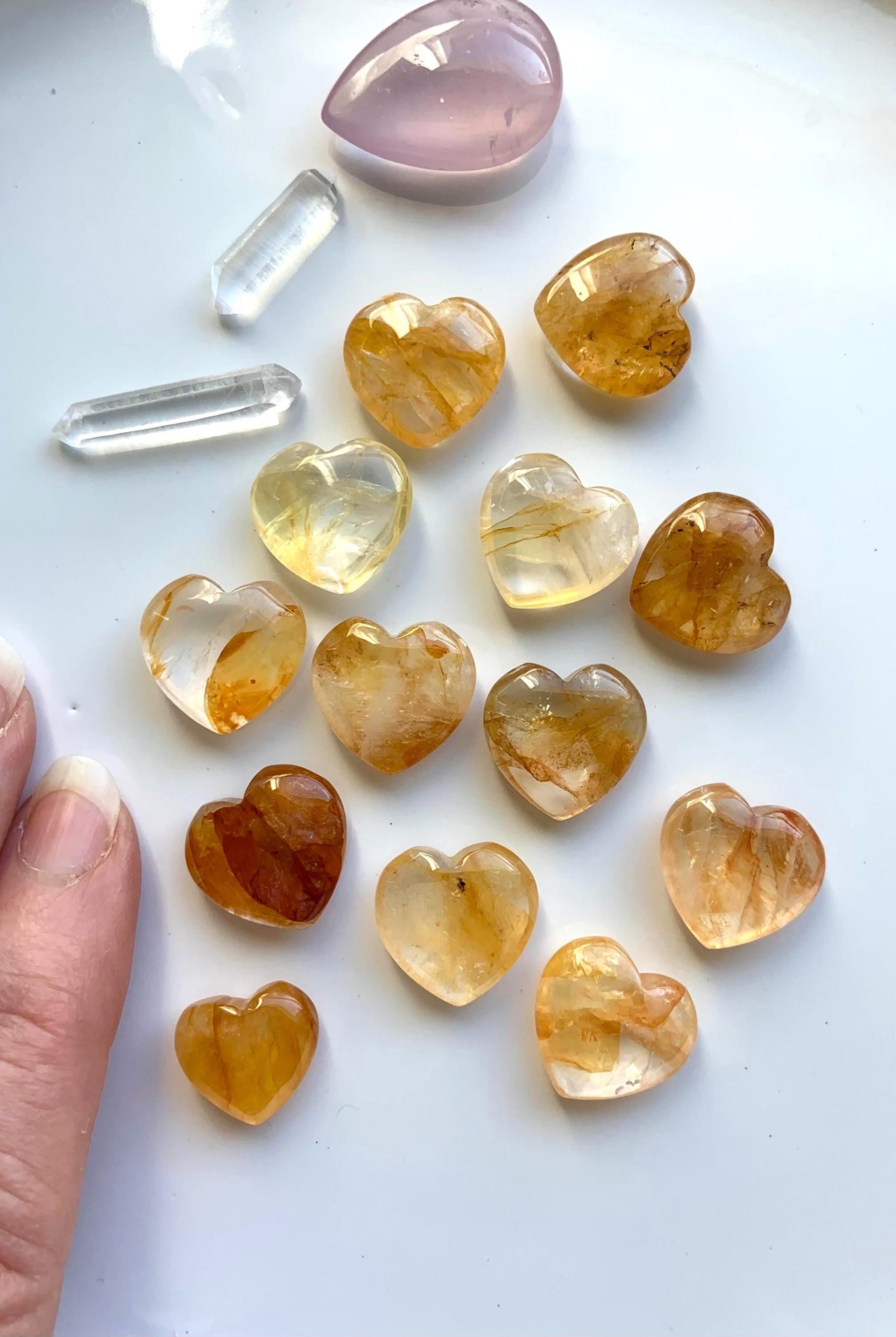 Golden Healer Heart Shaped Mini Crystal Carvings shown on a white plate with a few other crystals