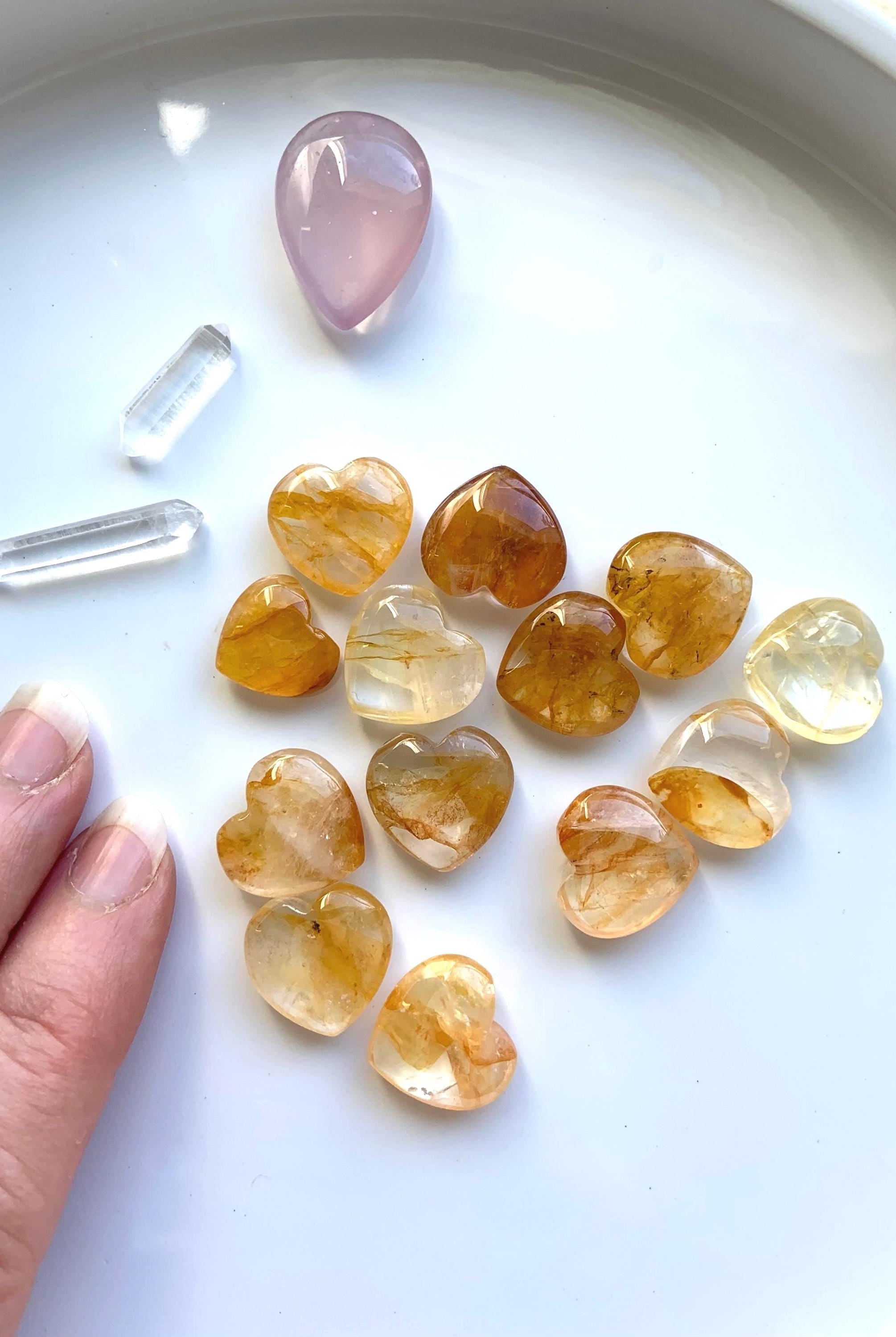 Tiny Golden Healer Crystal Hearts shown on a white plate with a few other crystals