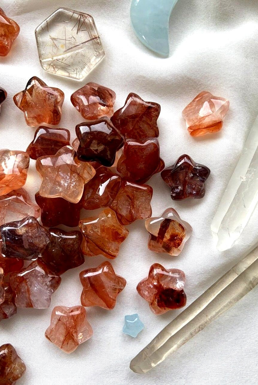 An array of vibrant red Mini Fire Quartz Crystal Star carvings shown on a white background