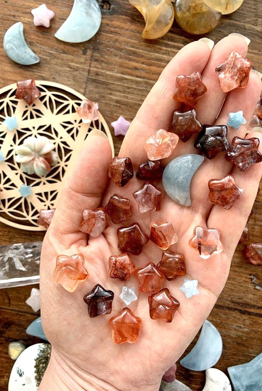 Mini Fire Quartz Crystal Stars shown on a my hand for scale with a crystal grid + crystal collection