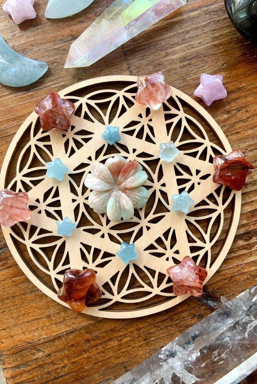 A crystal grid with Mini Fire Quartz Crystal Stars shown on a wood table with a crystal collection
