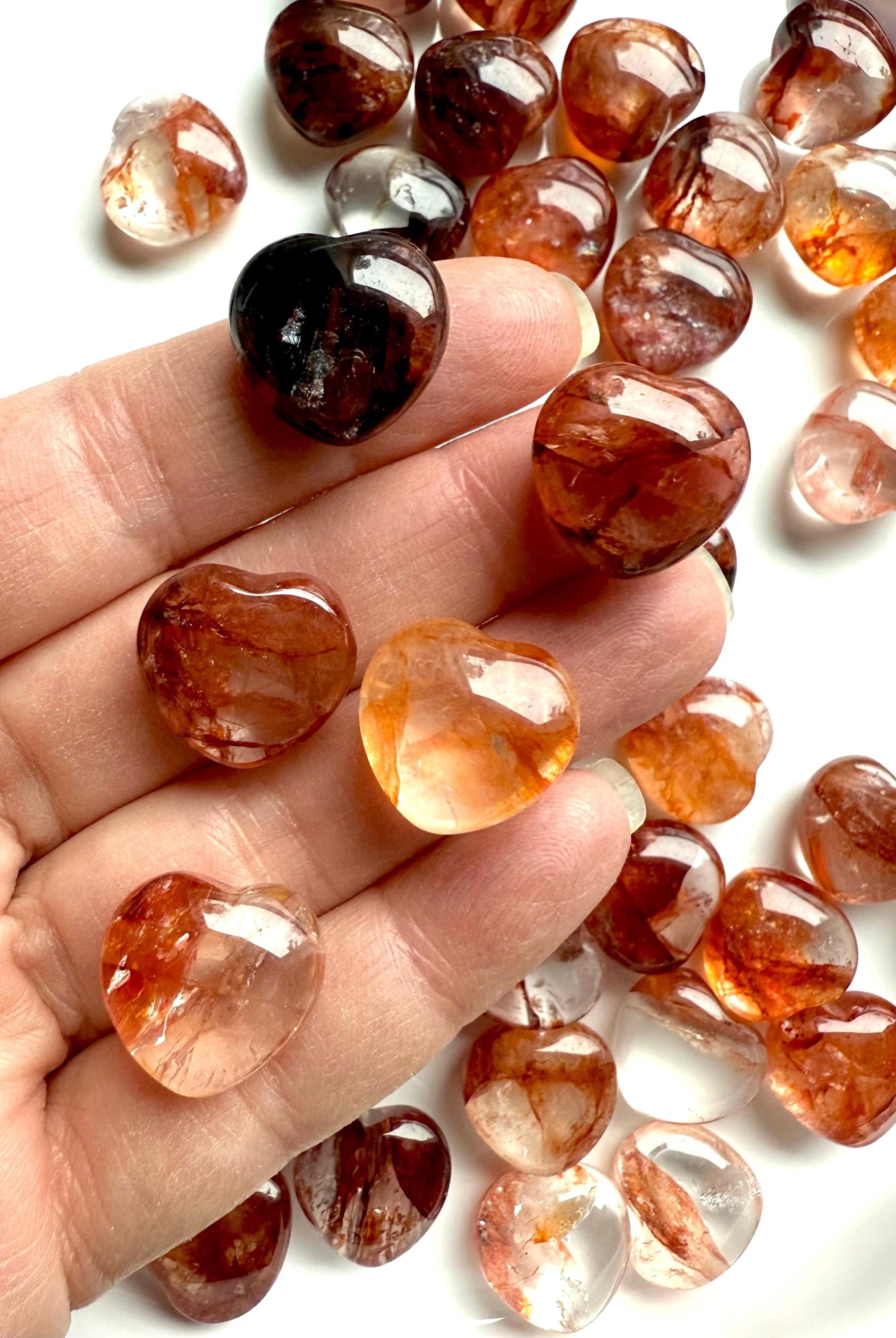 Close up of high quality Mini Fire Quartz Crystal Hearts shown on my fingertips for scale
