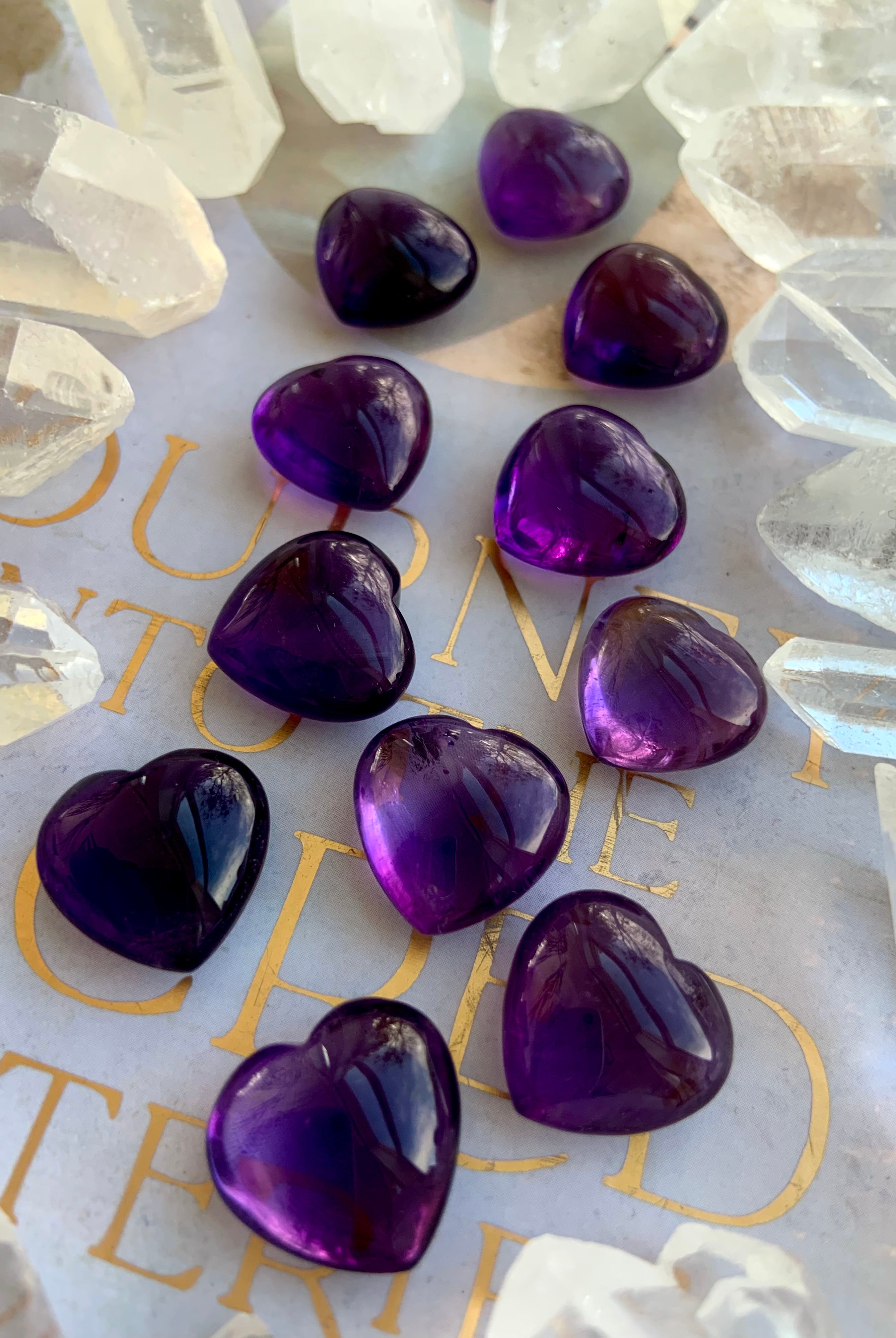 Angled shot of Mini Amethyst hearts surrounded by clear quartz points — purple crystal hearts for intuition and balance