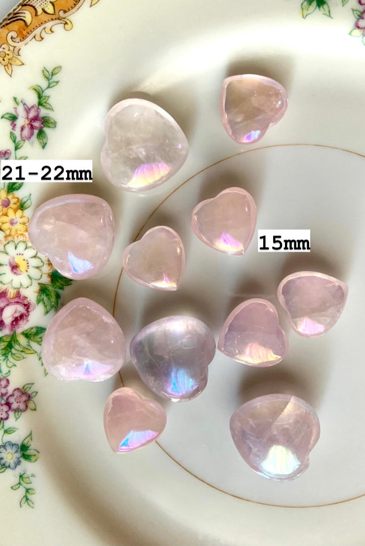 Translucent aura rose quartz hearts on a floral plate with sizes marked — dreamy pink crystals for emotional healing & heart-centered energy work
