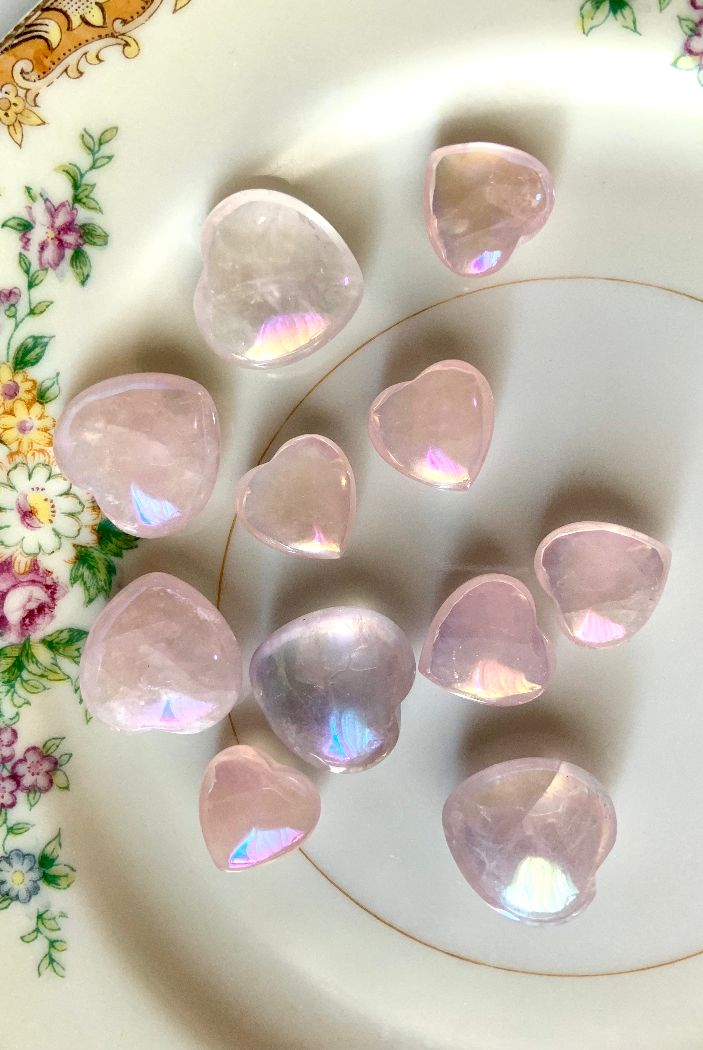 Close-up of translucent pink aura rose quartz hearts on a plate with floral cottagecore details — dreamy angel aura crystals for love & heart healing
