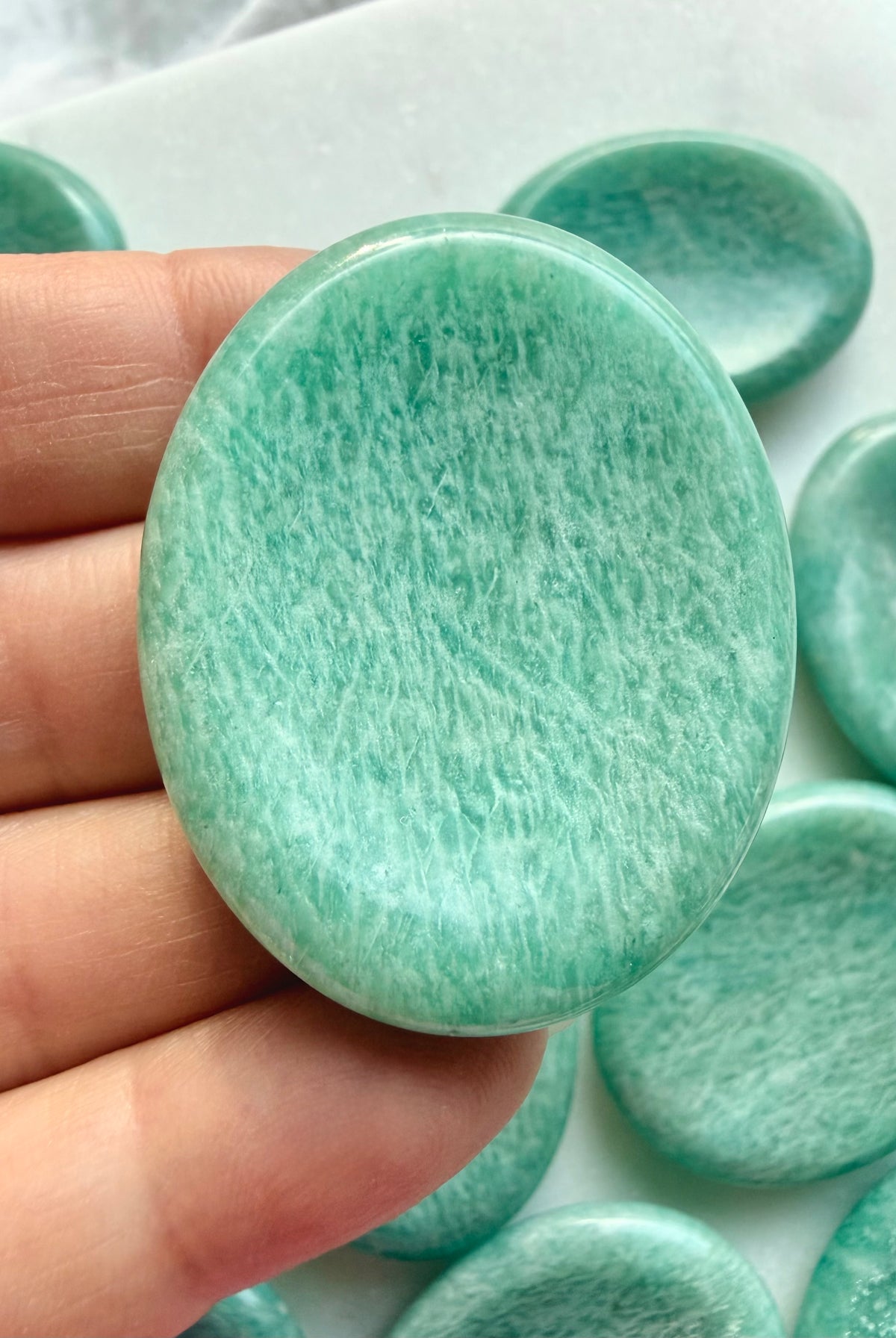 Close-up of polished Amazonite worry stone showing delicate mineral patterns, soft green coloring and a comfortable oval shape