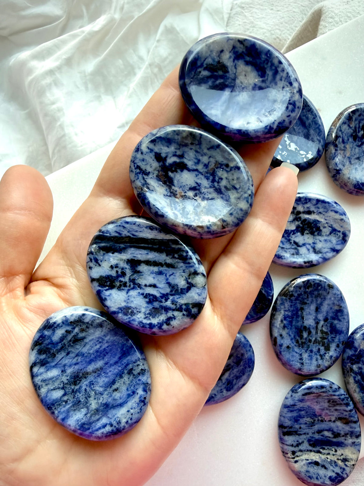 Natural Sodalite worry stones with rich blue and white marbling displayed in hand, polished thumb stones for stress relief and calming energy