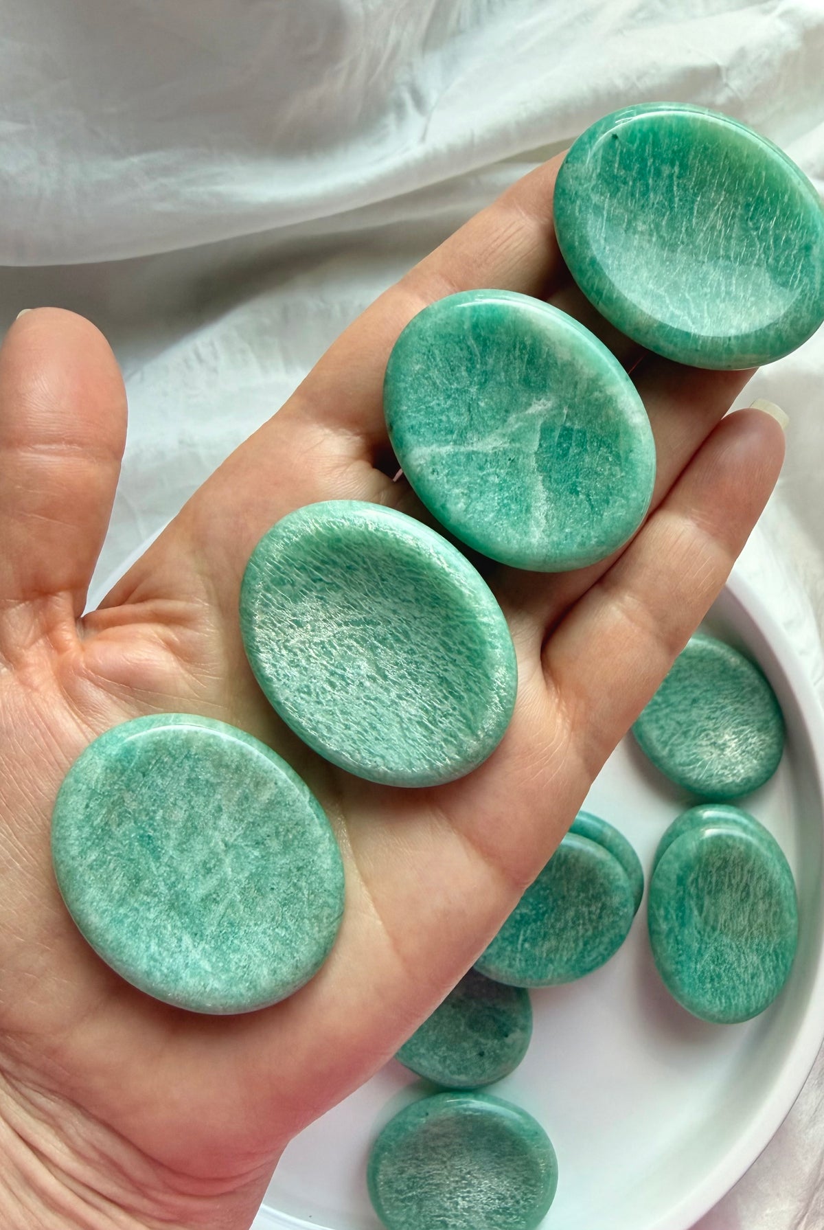Amazonite worry stones displayed in hand, smooth oval pocket crystals for Throat Chakra healing, communication and self-expression