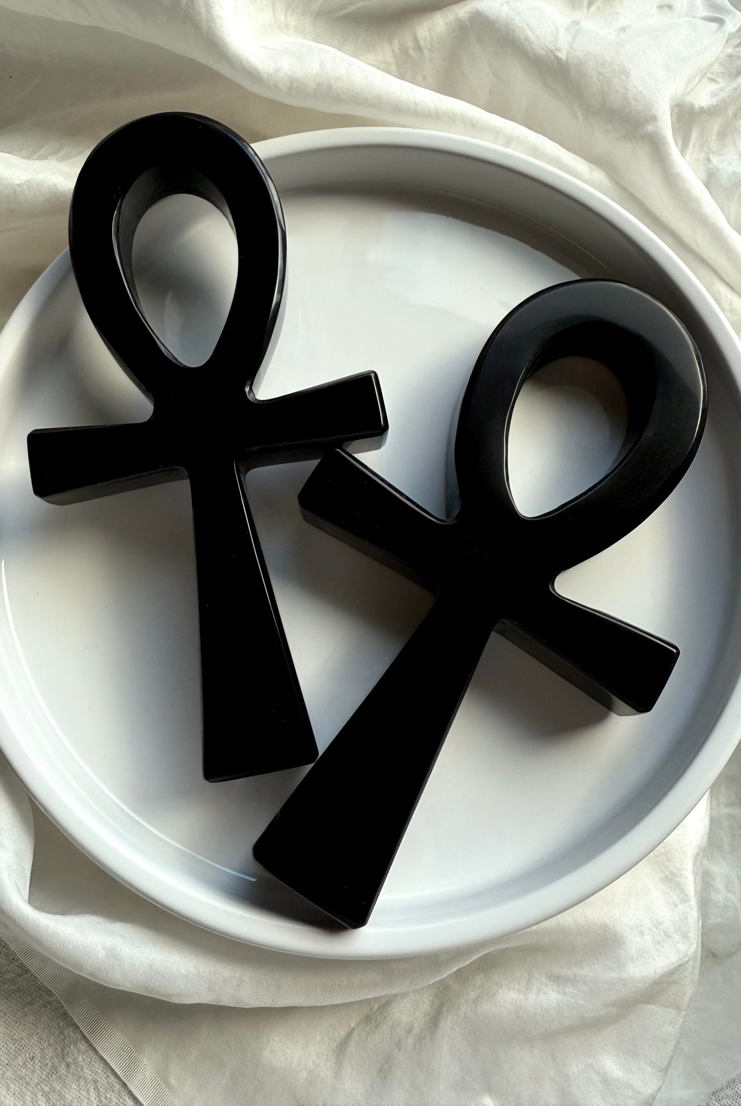 Two polished black obsidian ankh carvings side by side — Egyptian life symbol crystals for chakra alignment and meditation.
