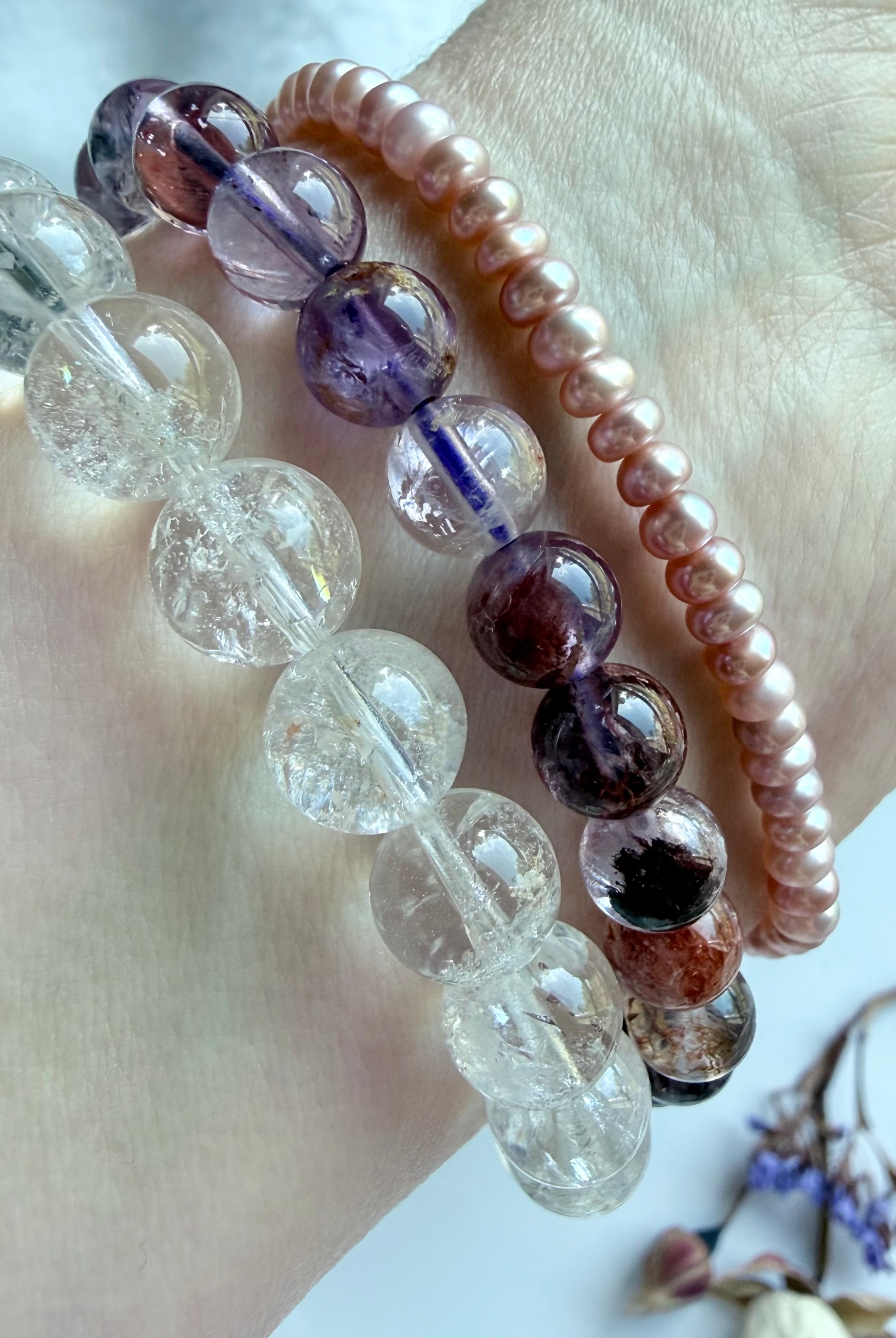 stacked crystal bracelets featuring Super Seven quartz, Rainbow Crackle Quartz, and pink pearl beads for feminine energy, emotional healing, intuition, and spiritual balance
