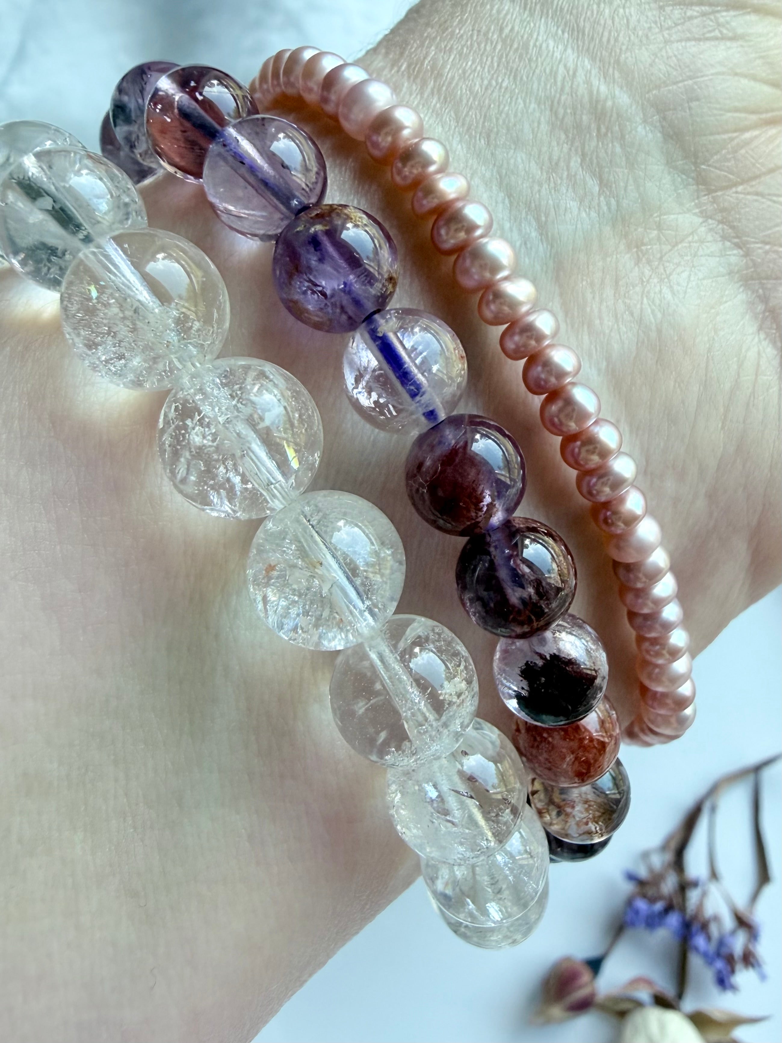 stacked crystal bracelets featuring Super Seven quartz, Rainbow Crackle Quartz, and pink pearl beads for feminine energy, emotional healing, intuition, and spiritual balance