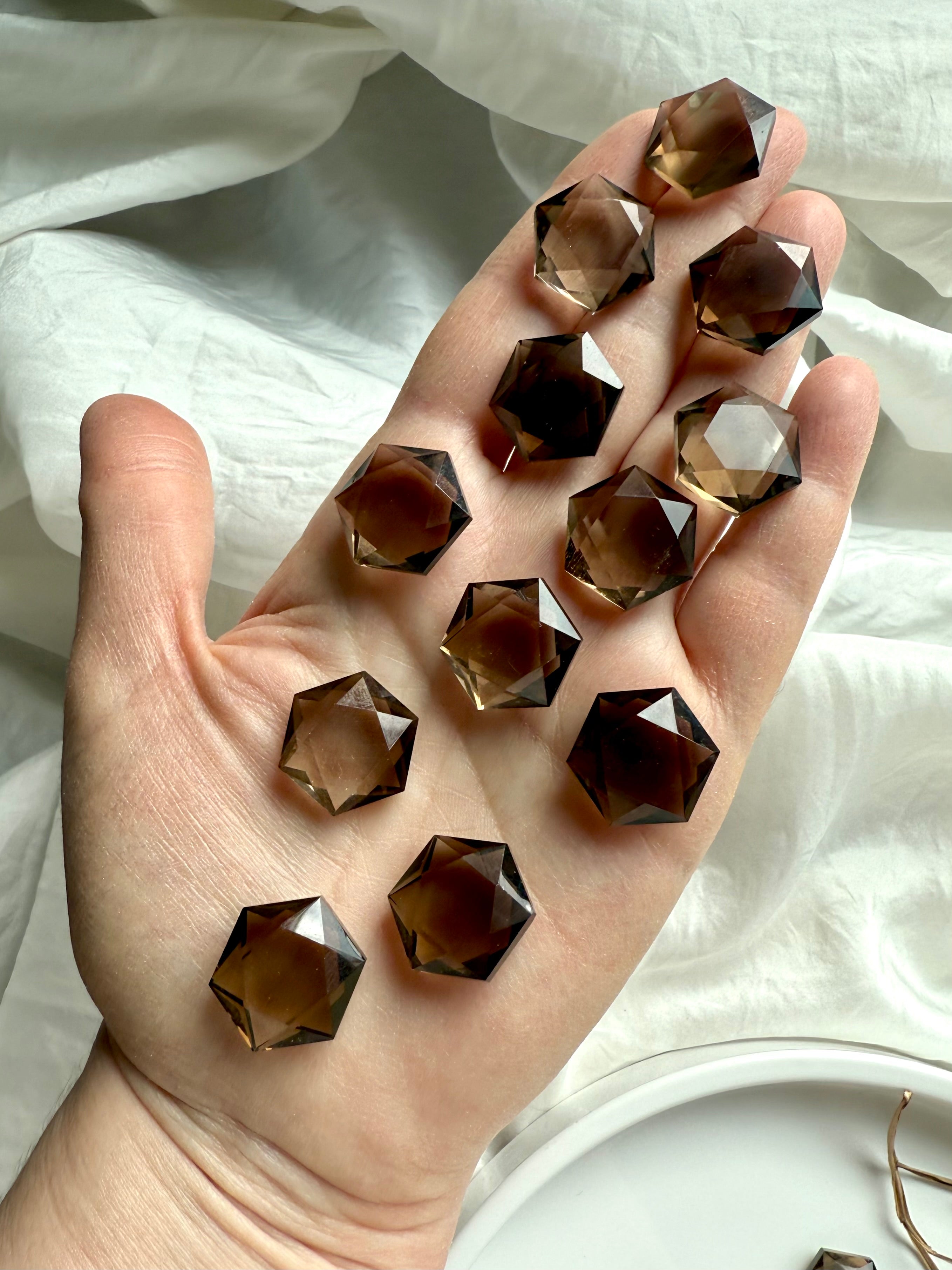 Hand holding faceted smoky quartz hexagons in natural light – Root Chakra crystals for grounding, clarity, and energetic protection.