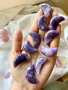 Purple Lepidolite Crescent Moon shaped crystal carvings shown on my hand for scale