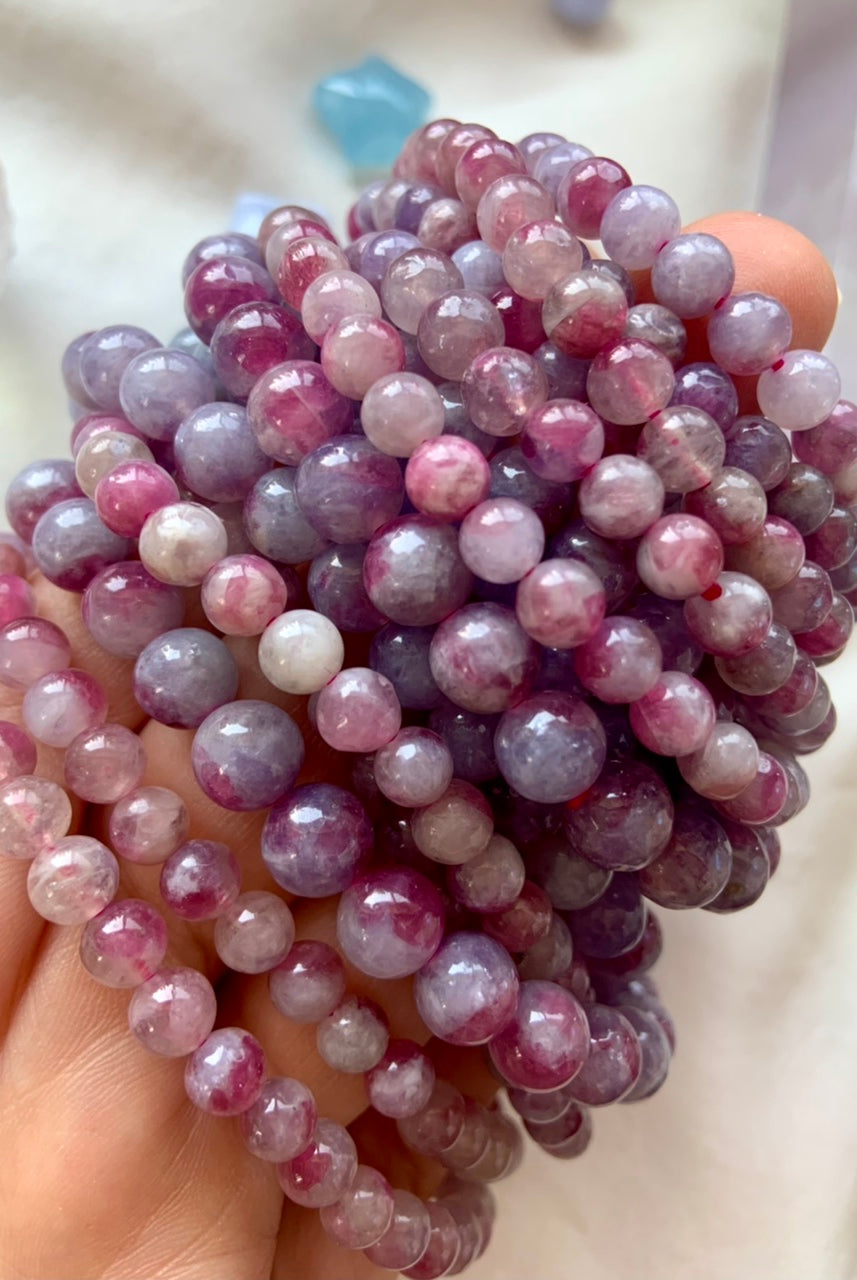 Side view of stacked Unicorn Stone bracelets in varying bead sizes — beaded crystal jewelry with Pink Tourmaline in Lepidolite for emotional balance + gentle energy.