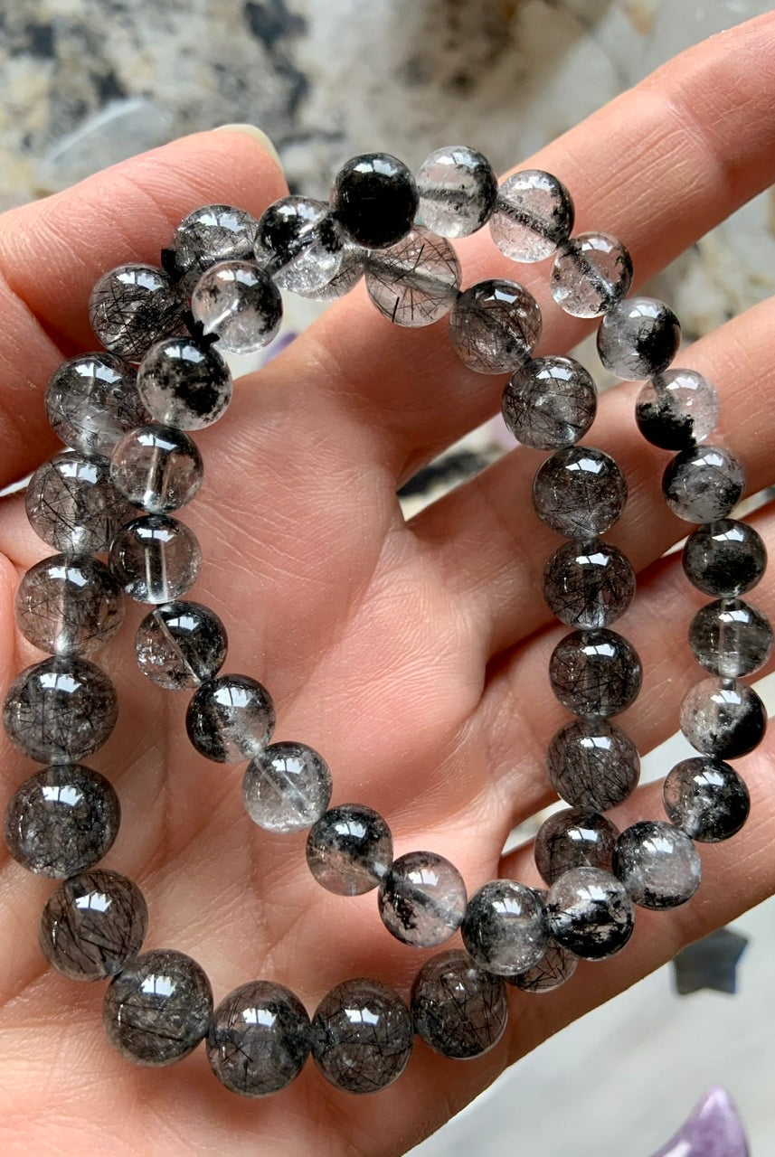Two Black Tourmaline in Quartz bracelets worn on a hand, showing clarity and fine tourmaline inclusions