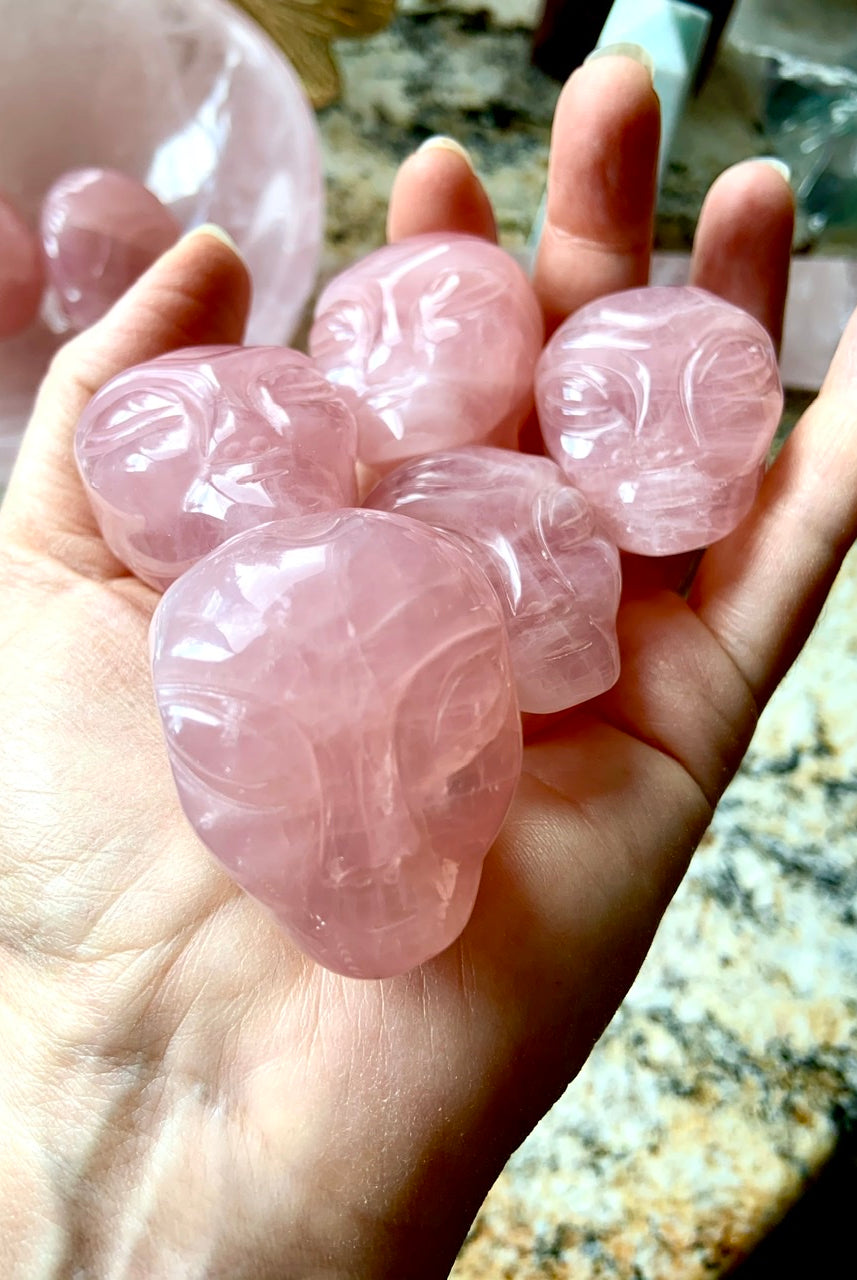Rose Quartz alien head carving with large eyes and defined brow, shown in a pink crystal bowl on altar