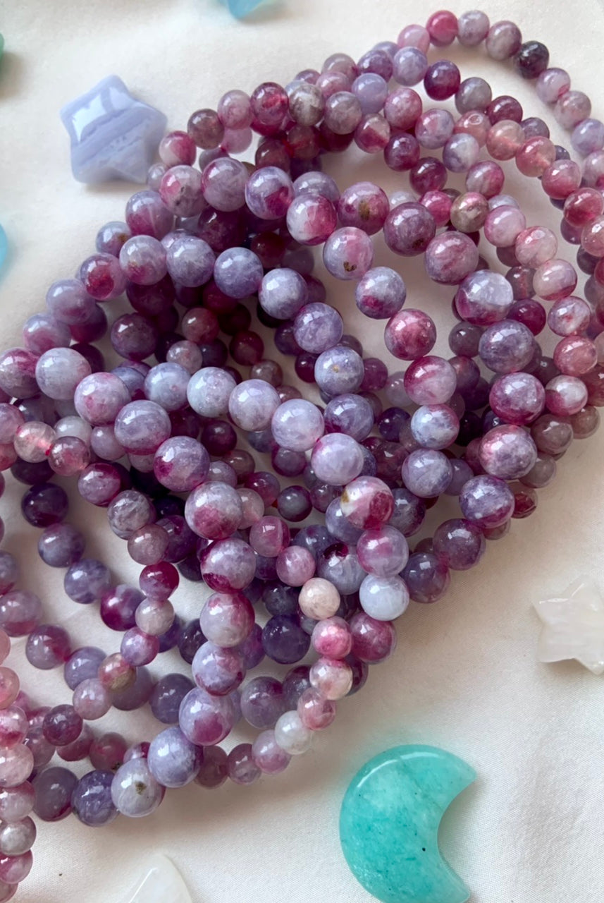 Array of Unicorn Stone crystal bracelets on white silk surrounded by celestial crystals — soothing energy tools for emotional healing + spiritual calm.