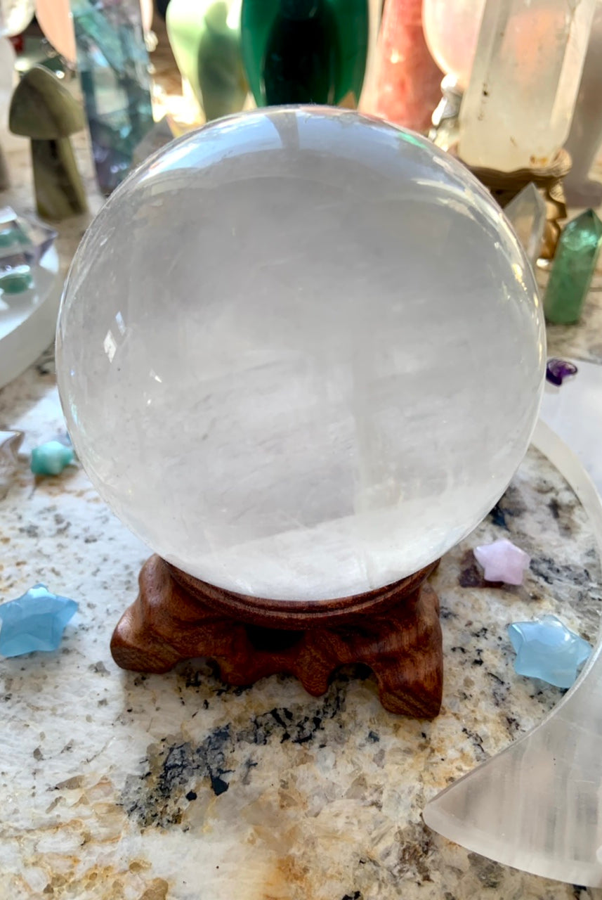 an optical calcite sphere on a wood stand with a crystal collection in the background