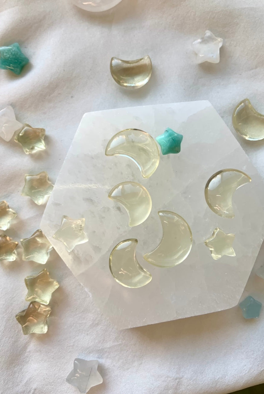 Overhead view of mini citrine stars and moons on selenite plate with celestial mini crystals — joyful citrine carvings for chakra healing